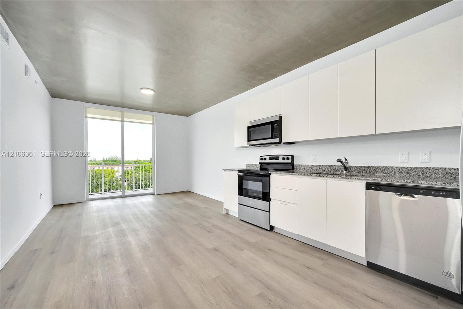 Kitchen featuring flat-panel cabinetry, stone countertops, stainless steel appliances, wood-finish flooring, and a sliding glass door