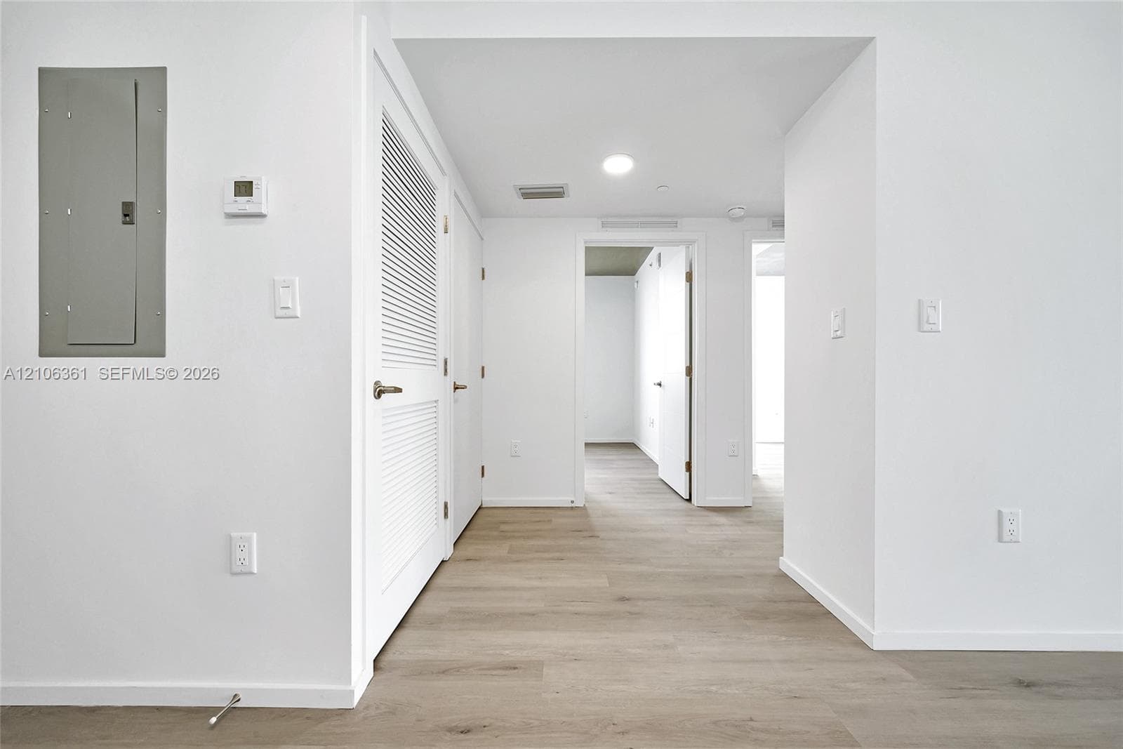 Interior corridor featuring wood-finish flooring, recessed lighting, and louvered closet doors