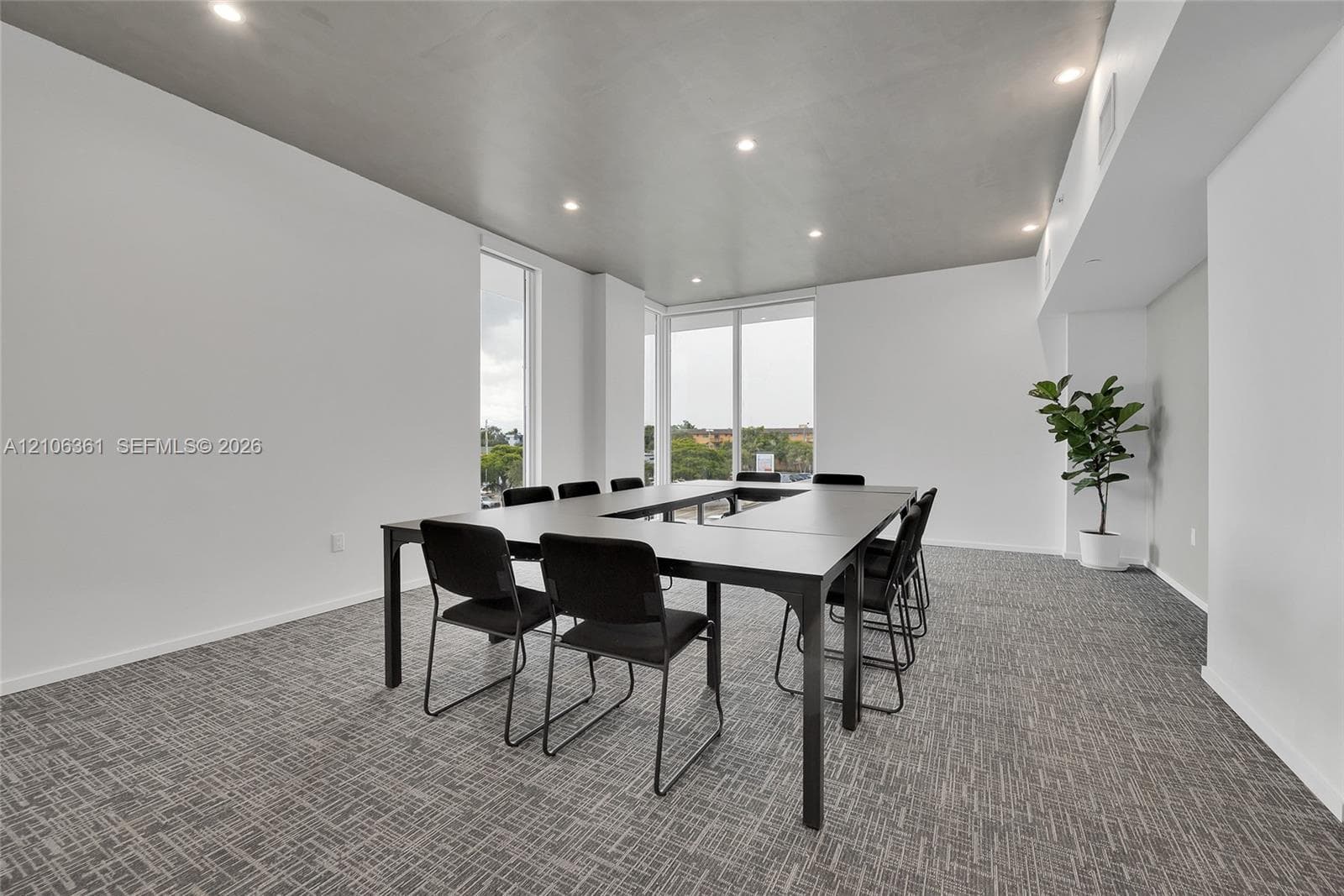 Interior space featuring floor-to-ceiling windows, high ceilings with recessed lighting, and neutral patterned carpeting