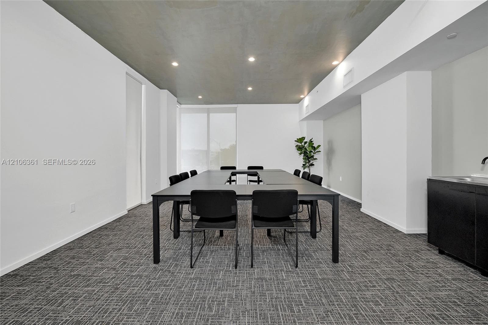 Neutral-toned room featuring a smooth grey ceiling, recessed lighting, textured carpet flooring, and a built-in black wet bar cabinet