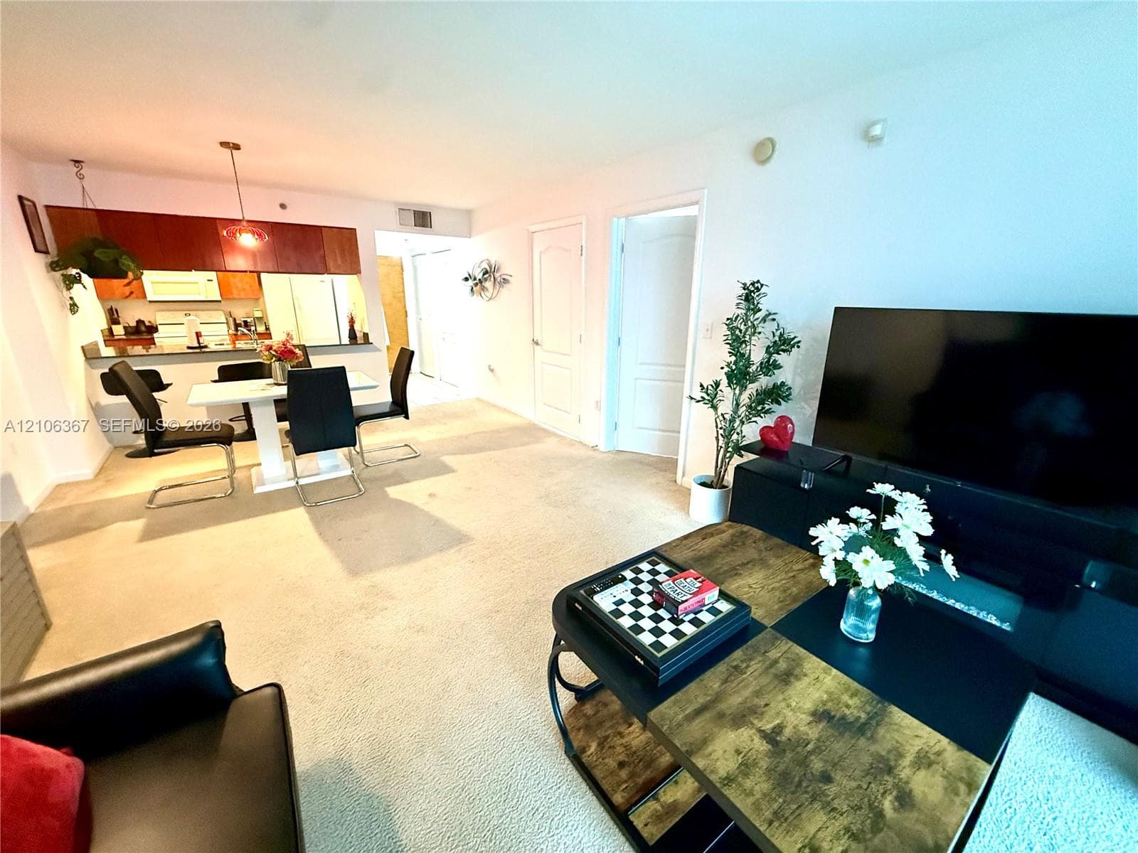 Open-concept interior featuring wood-finish cabinetry, neutral carpeting, and solid-core interior doors