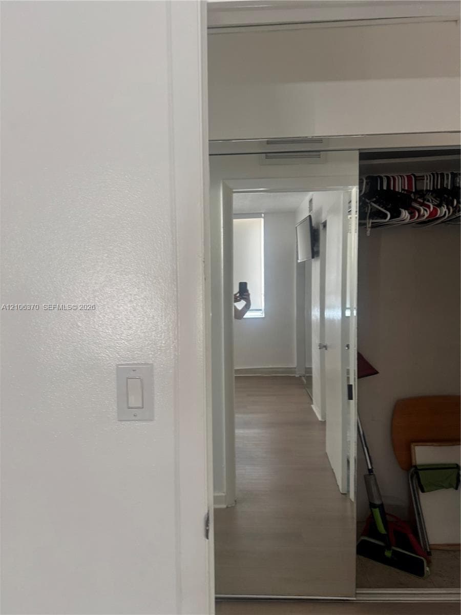 Sliding mirrored closet doors featuring a metal frame, neutral walls, and light-toned wood-finish flooring