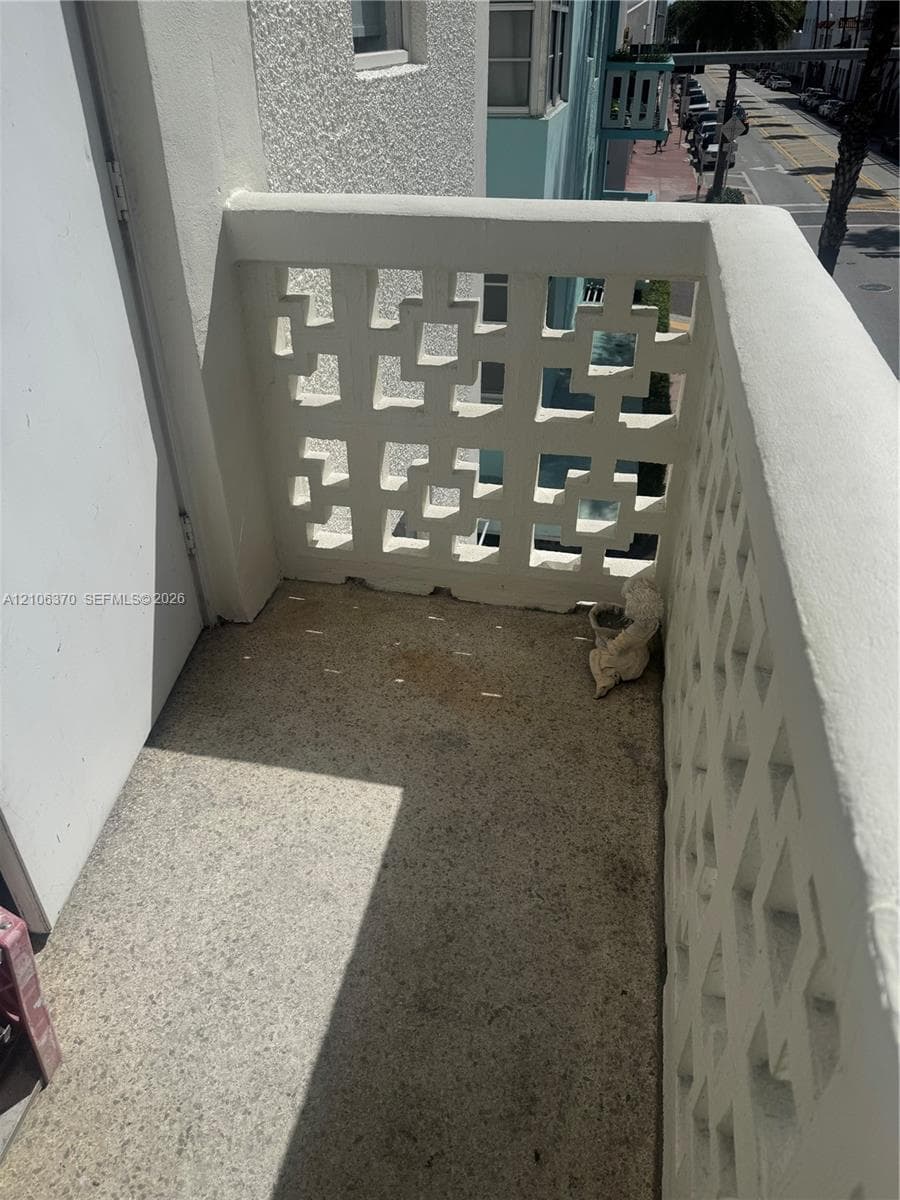 Private balcony featuring decorative geometric concrete screening and textured mineral-composite flooring
