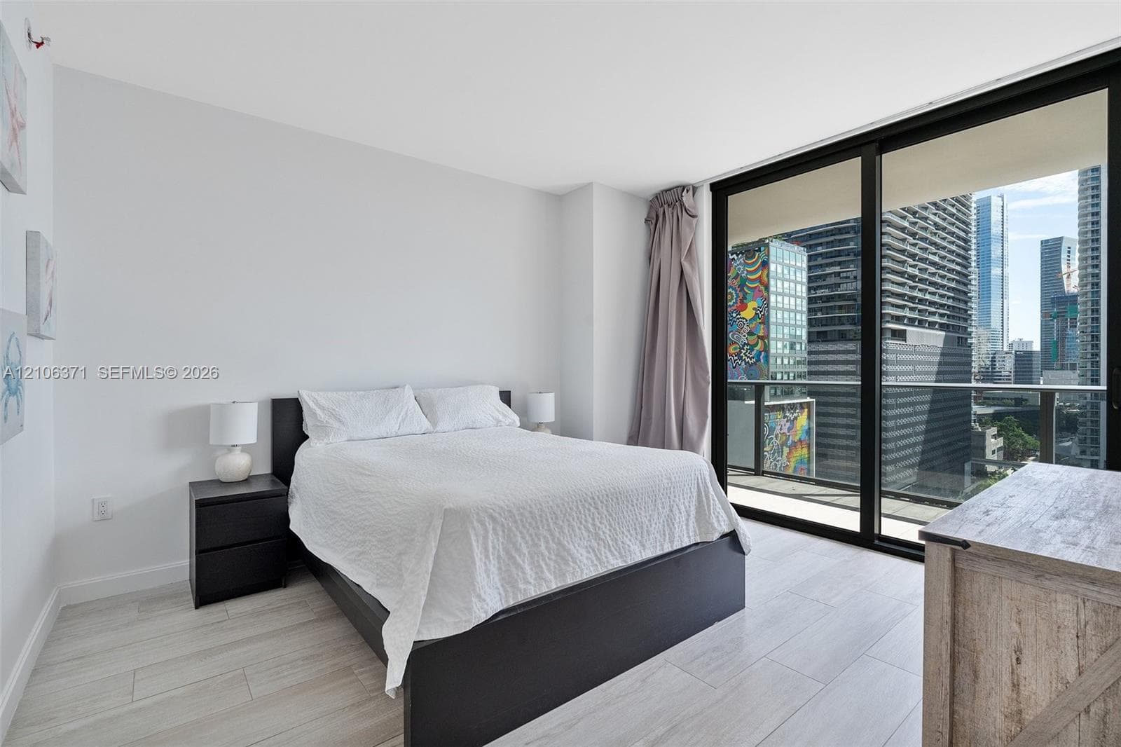 Floor-to-ceiling glass sliding doors, private balcony, and light wood-finish flooring