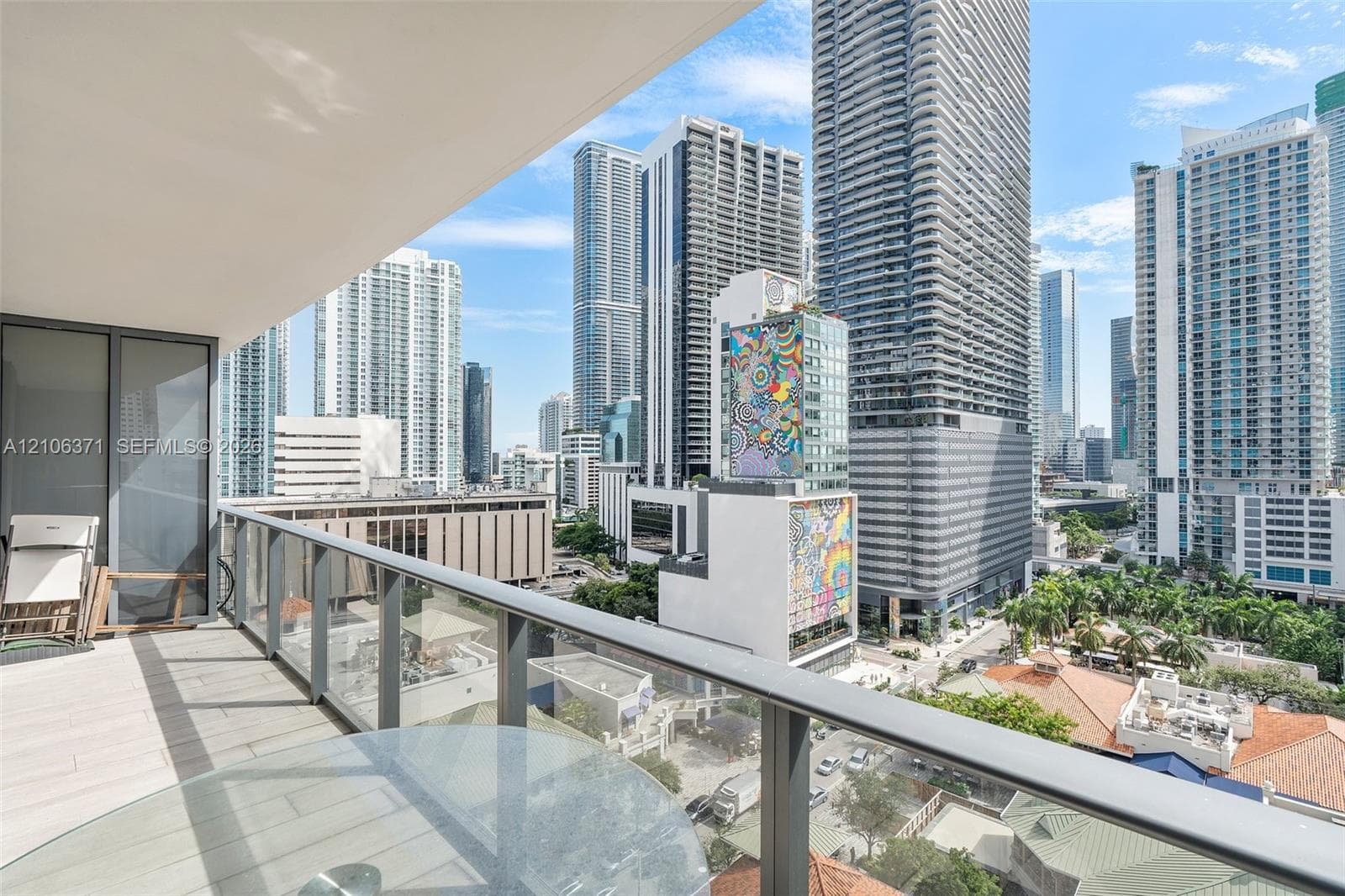 Covered balcony featuring large-format tile flooring and a glass-paneled metal railing