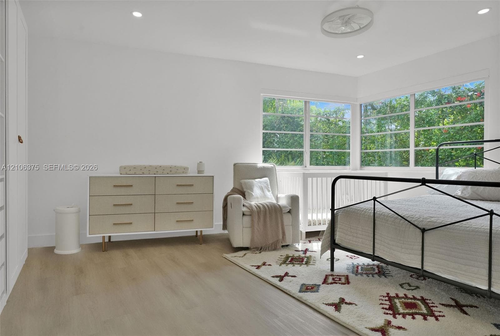 Room featuring wood-finish flooring, corner windows, recessed lighting, a ceiling fan, and built-in floor-to-ceiling cabinetry