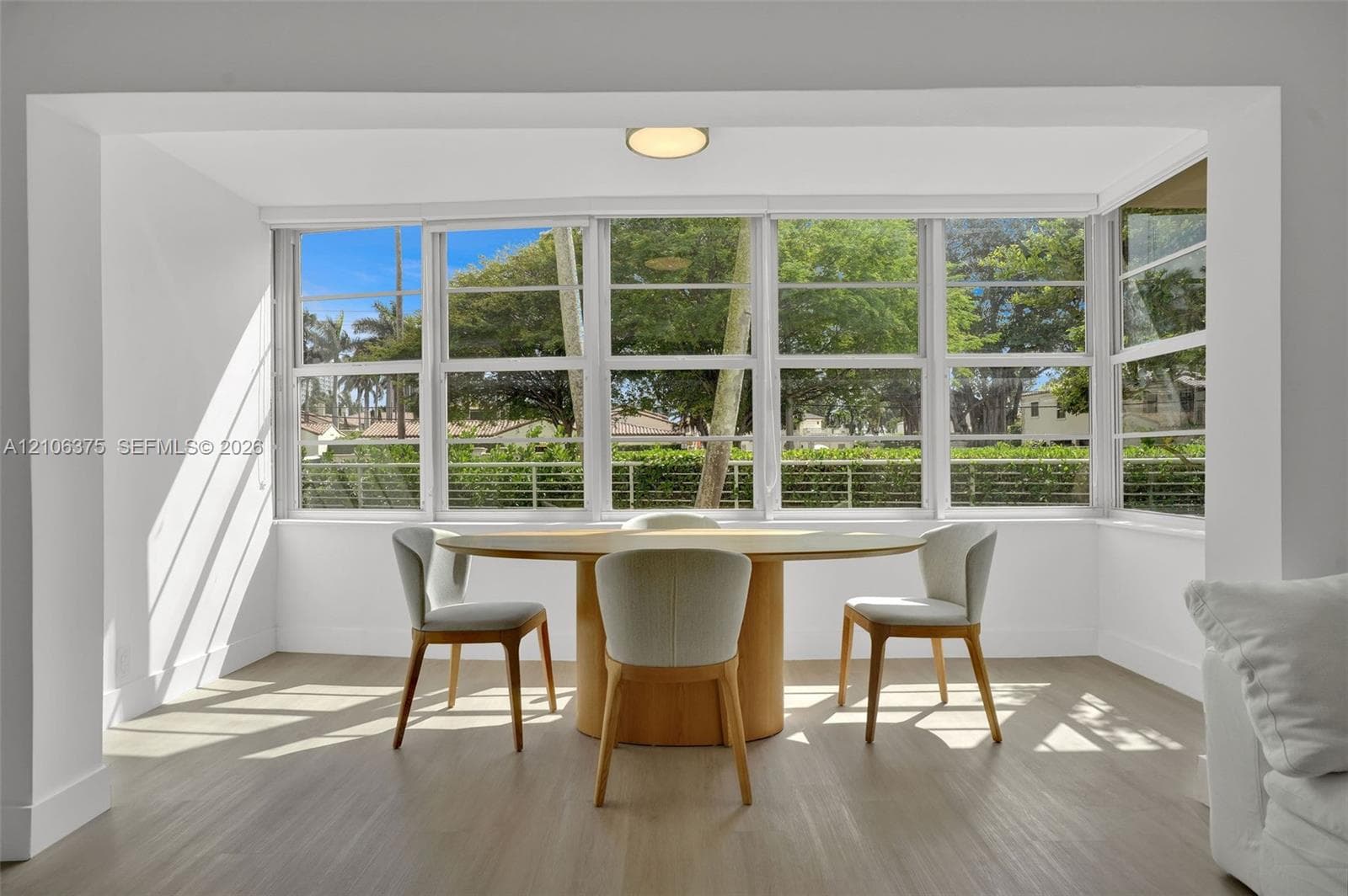 Expansive window wall with white frames, wood-finish flooring, and recessed ceiling lighting