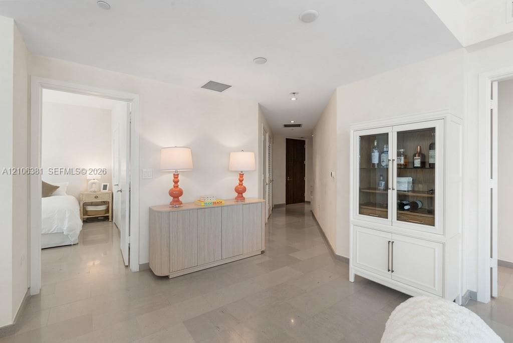 Hallway featuring neutral tile flooring, recessed ceiling lighting, and crisp white wall finishes
