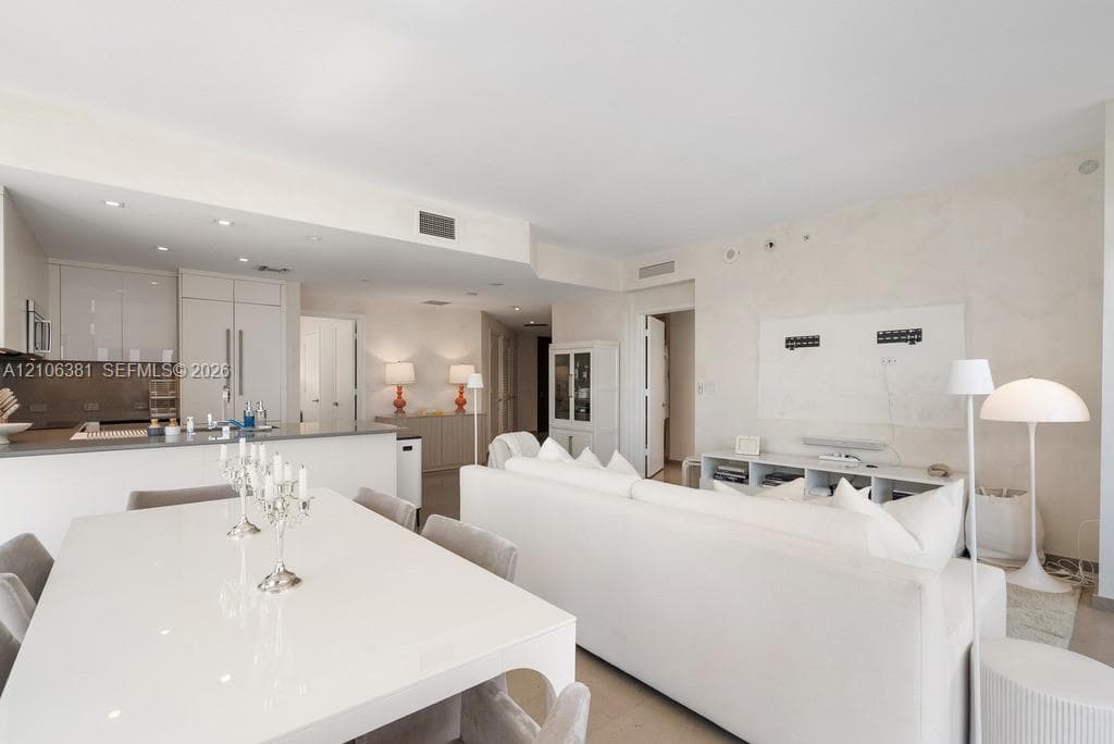 Open-concept interior featuring high-gloss cabinetry, stone-surfaced kitchen island, recessed ceiling lighting, and neutral-toned flooring