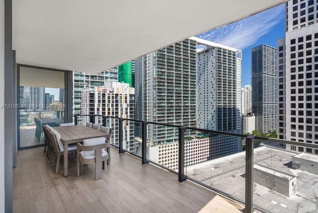 Covered balcony featuring wood-finish flooring and a glass panel railing with a dark metal frame