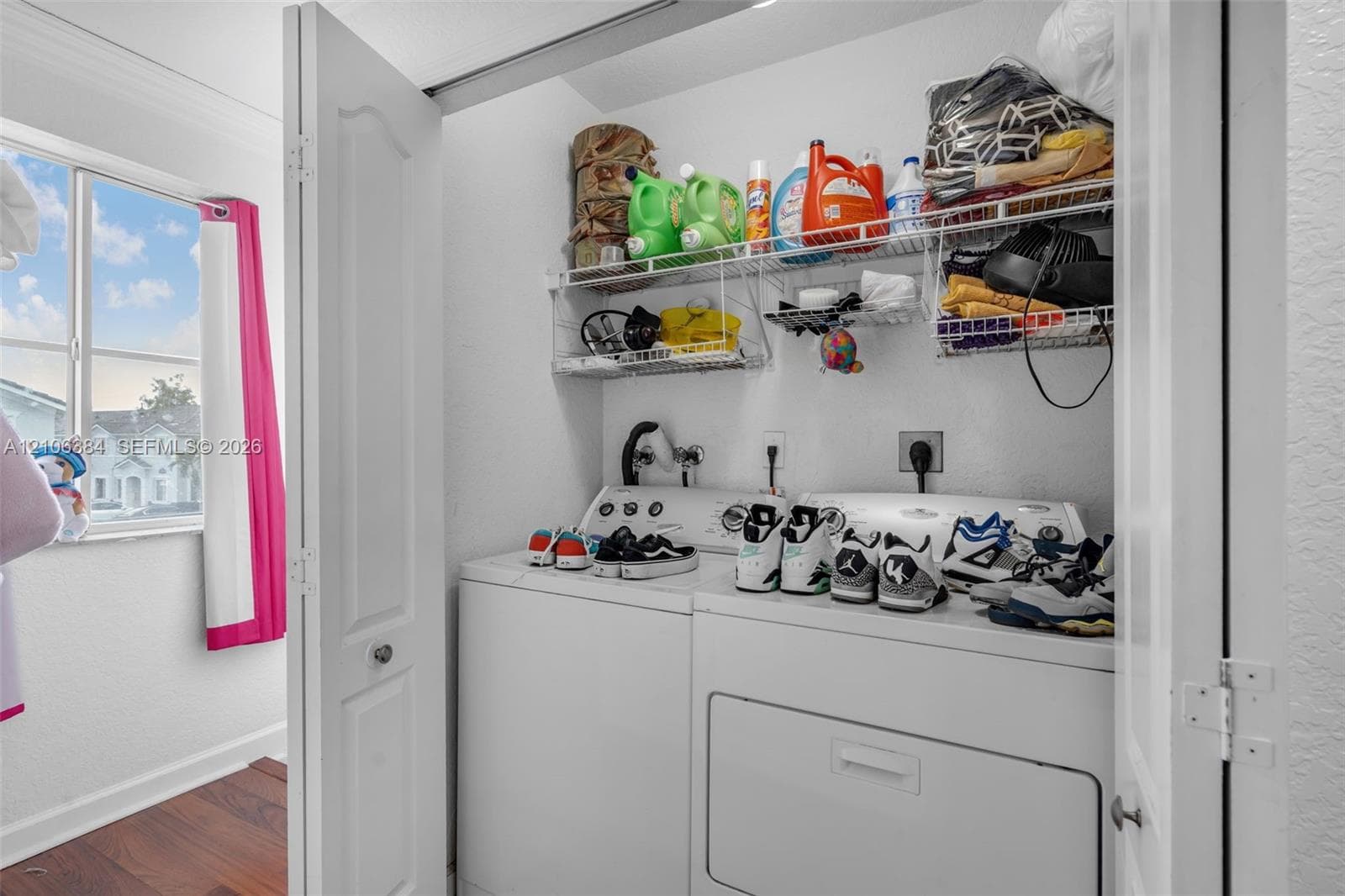 Laundry closet featuring dual-fold doors, white appliance hookups, and integrated wire shelving