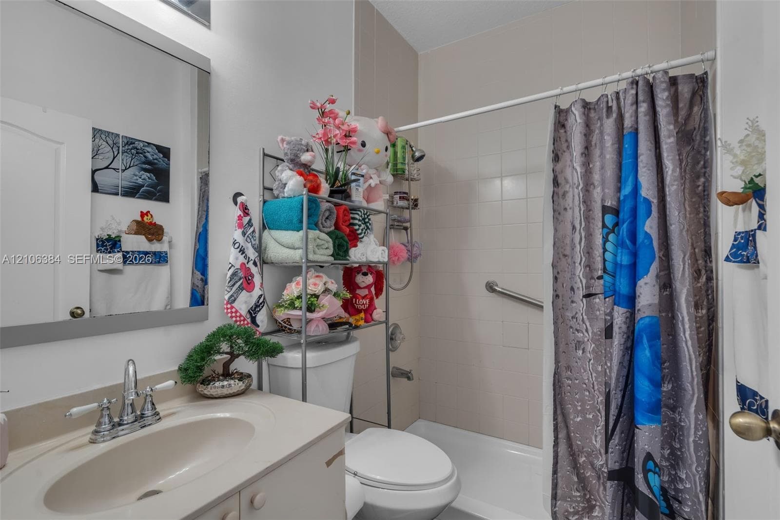 Bathroom featuring a vanity with an integrated basin, chrome dual-handle faucet, framed wall mirror, and a tub-shower combination with ceramic tile surround and installed safety grab bar