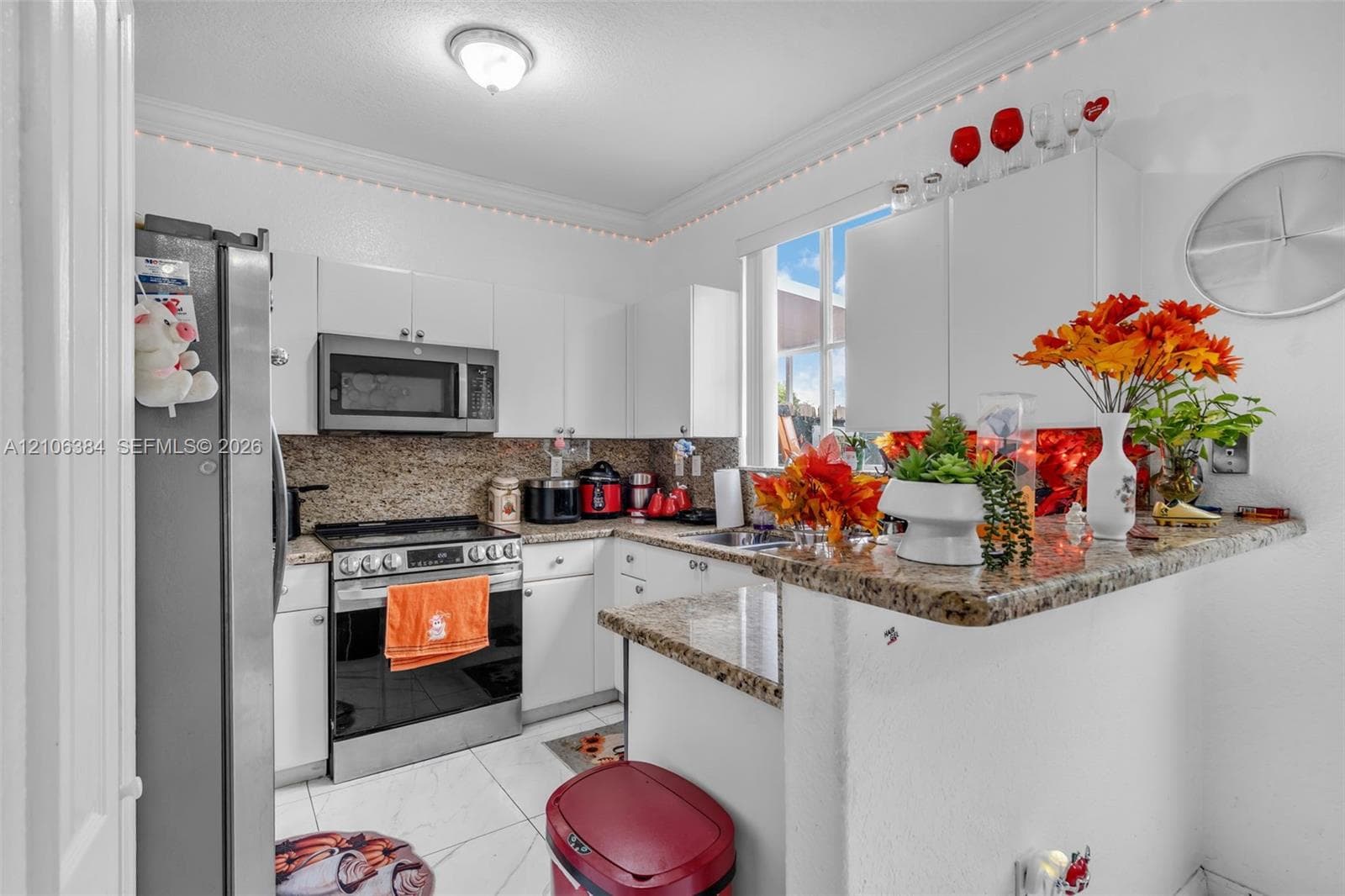 Kitchen featuring white cabinetry, stone-finish countertops, stainless steel appliances, a tile floor, and crown molding