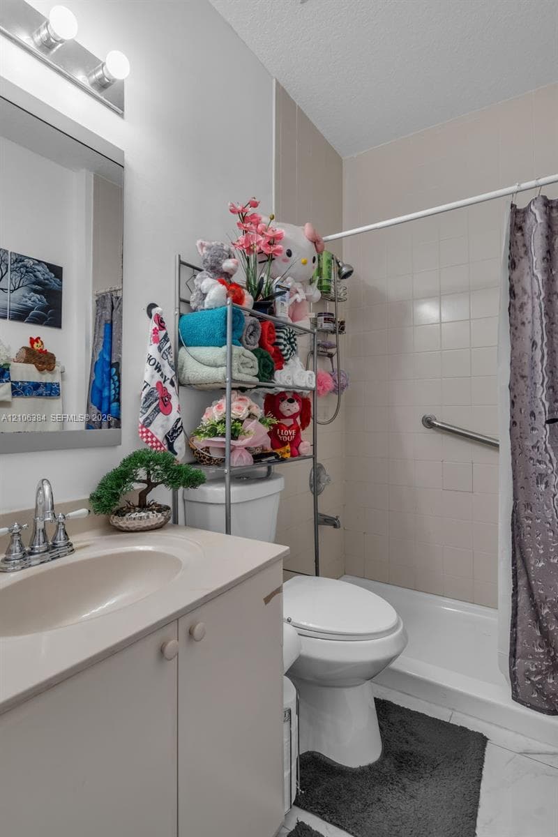 Bathroom featuring a vanity with an integrated sink, a wall-mounted vanity mirror, a dual-light fixture, and a bathtub with a tiled surround and grab bar