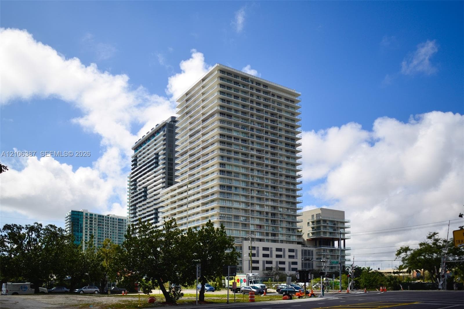 High-rise residential tower featuring a concrete facade, tiered floor levels, glass balcony railings, and a multi-story podium structure