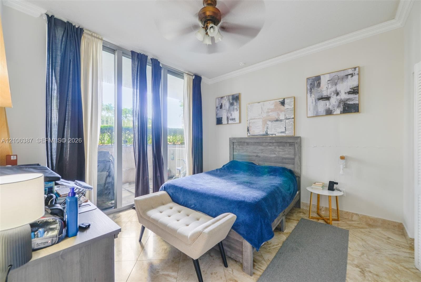 Full-height glass panel doors, polished stone tile flooring, crown molding, and a central ceiling fan