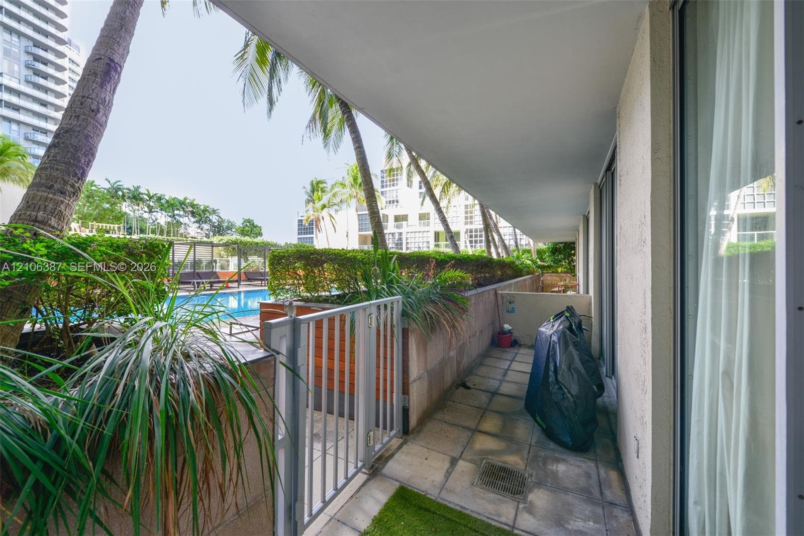 Covered patio featuring tiled flooring, a metal security gate, and masonry planters