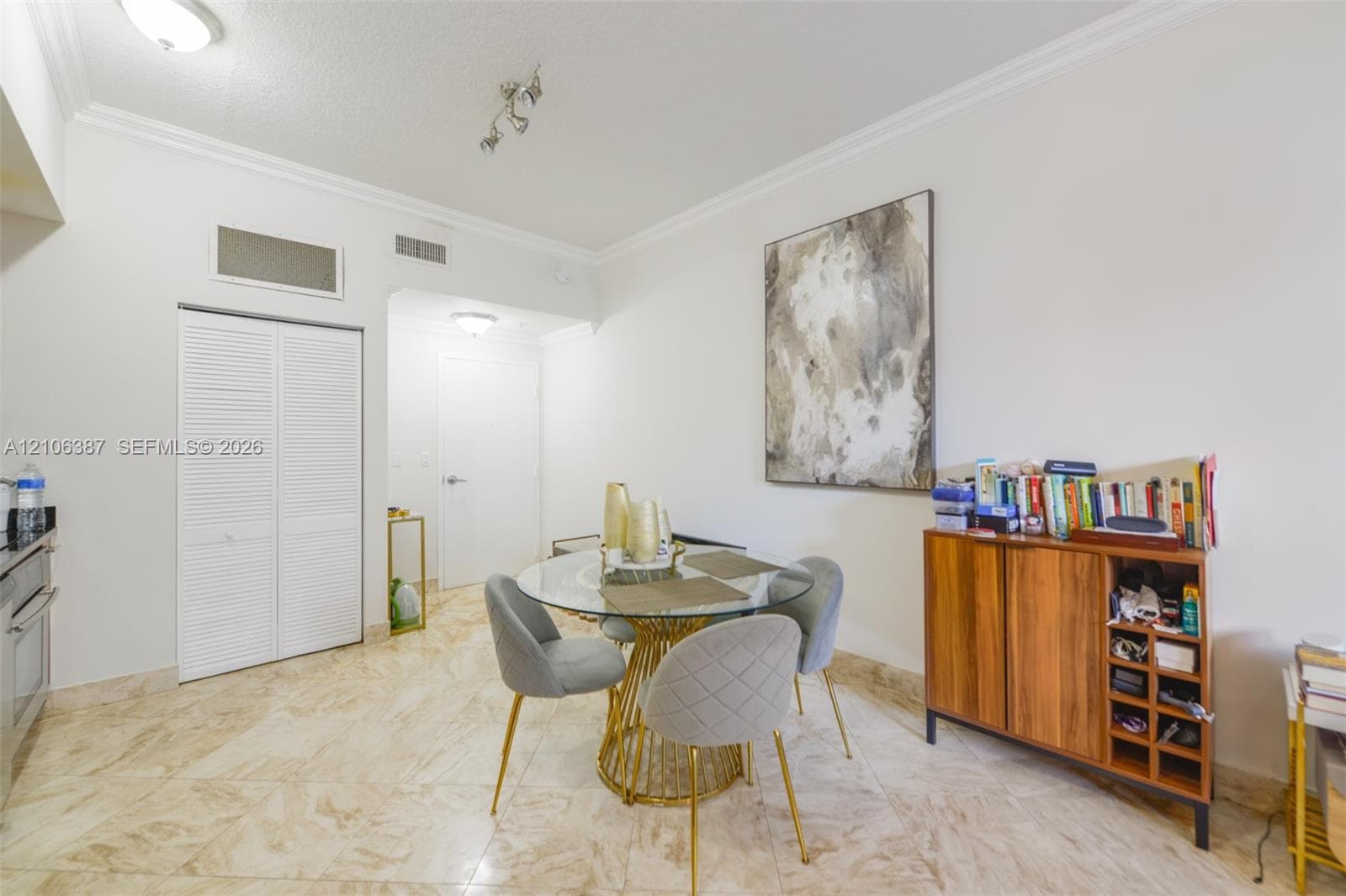 Neutral-toned tile flooring, white walls with crown molding, and louvered double-door closet
