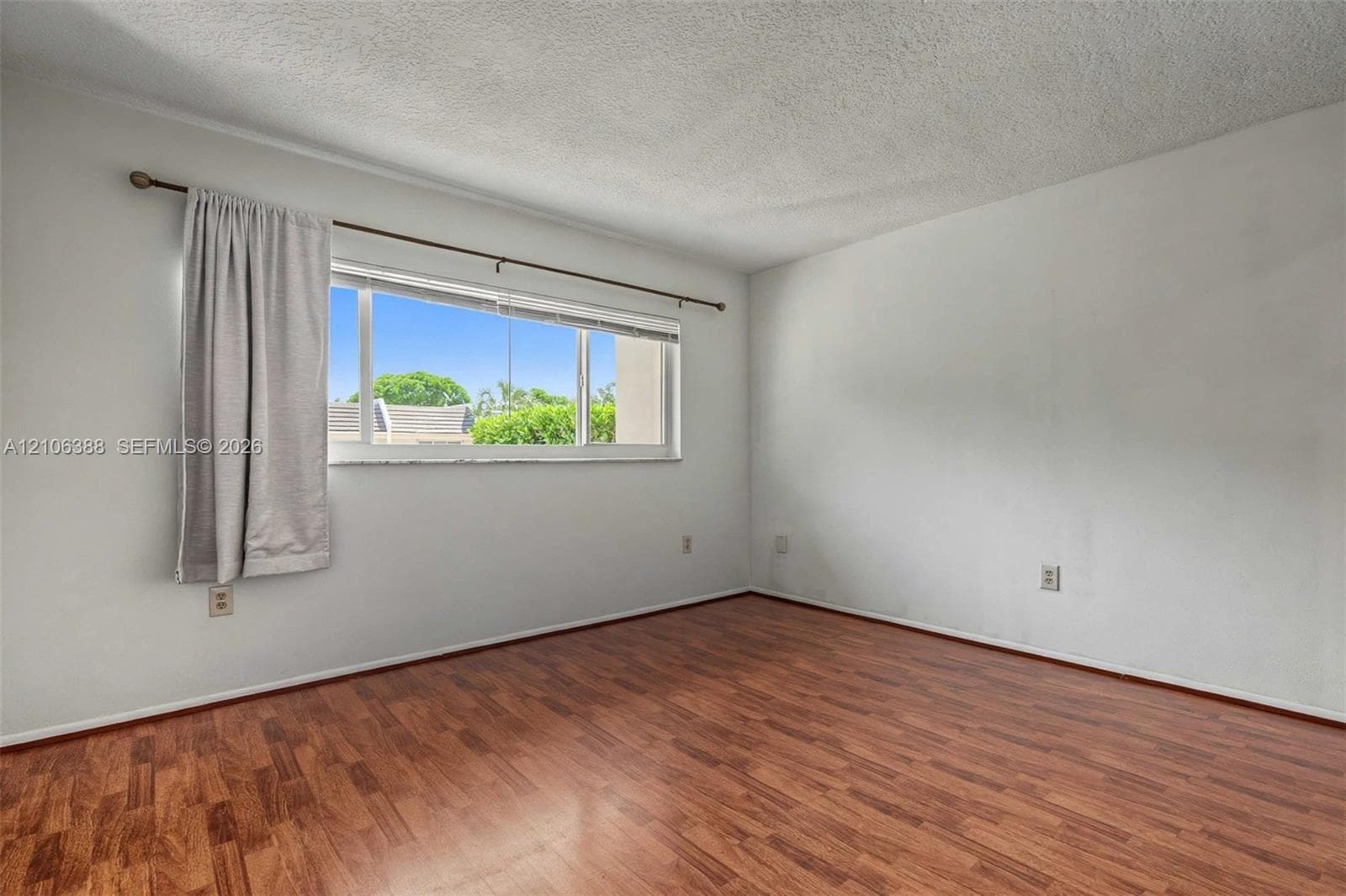Interior room featuring wood-finish flooring, a multi-pane horizontal window, and a textured ceiling