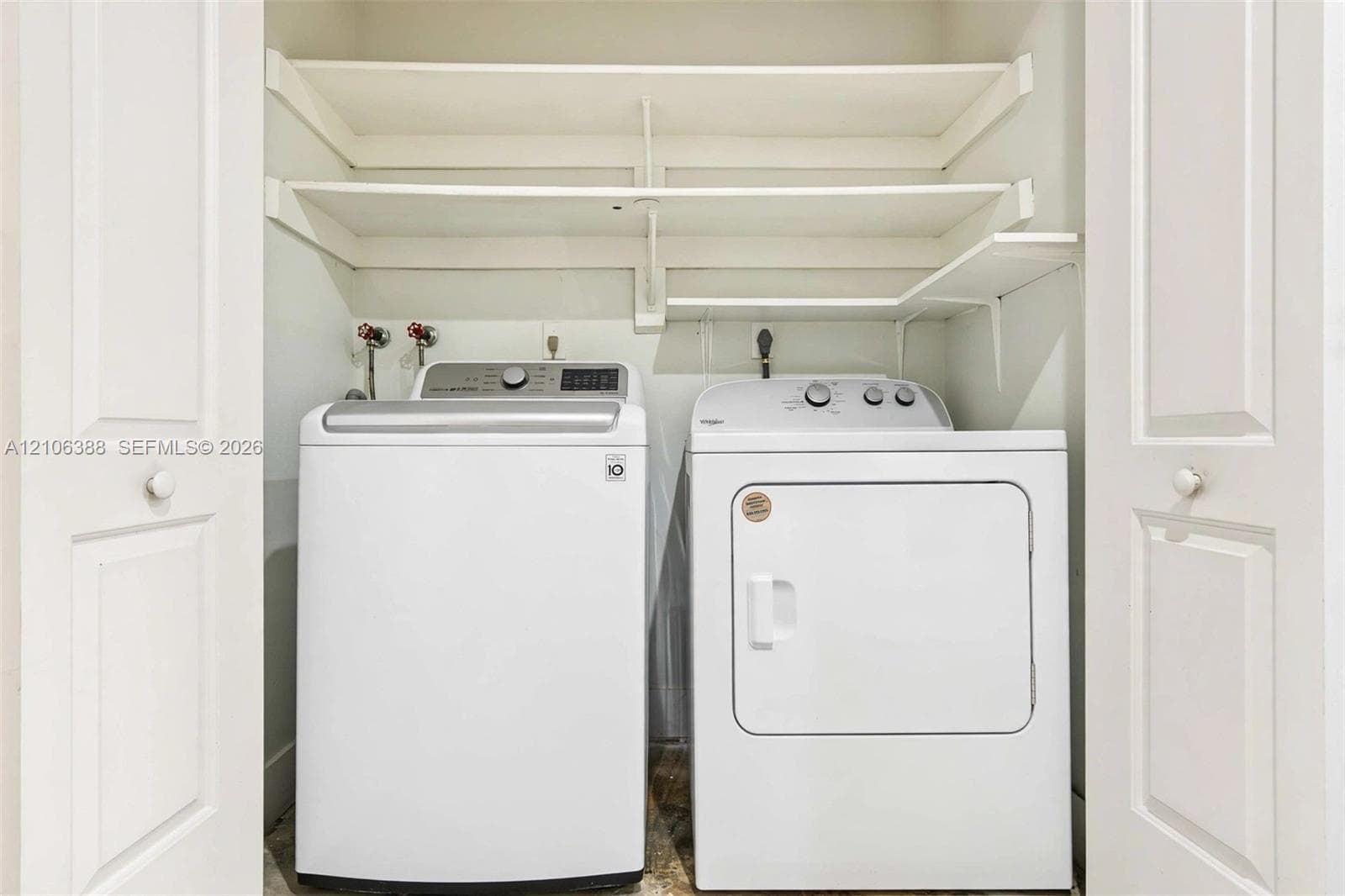 Laundry closet featuring white bifold doors and integrated tiered shelving
