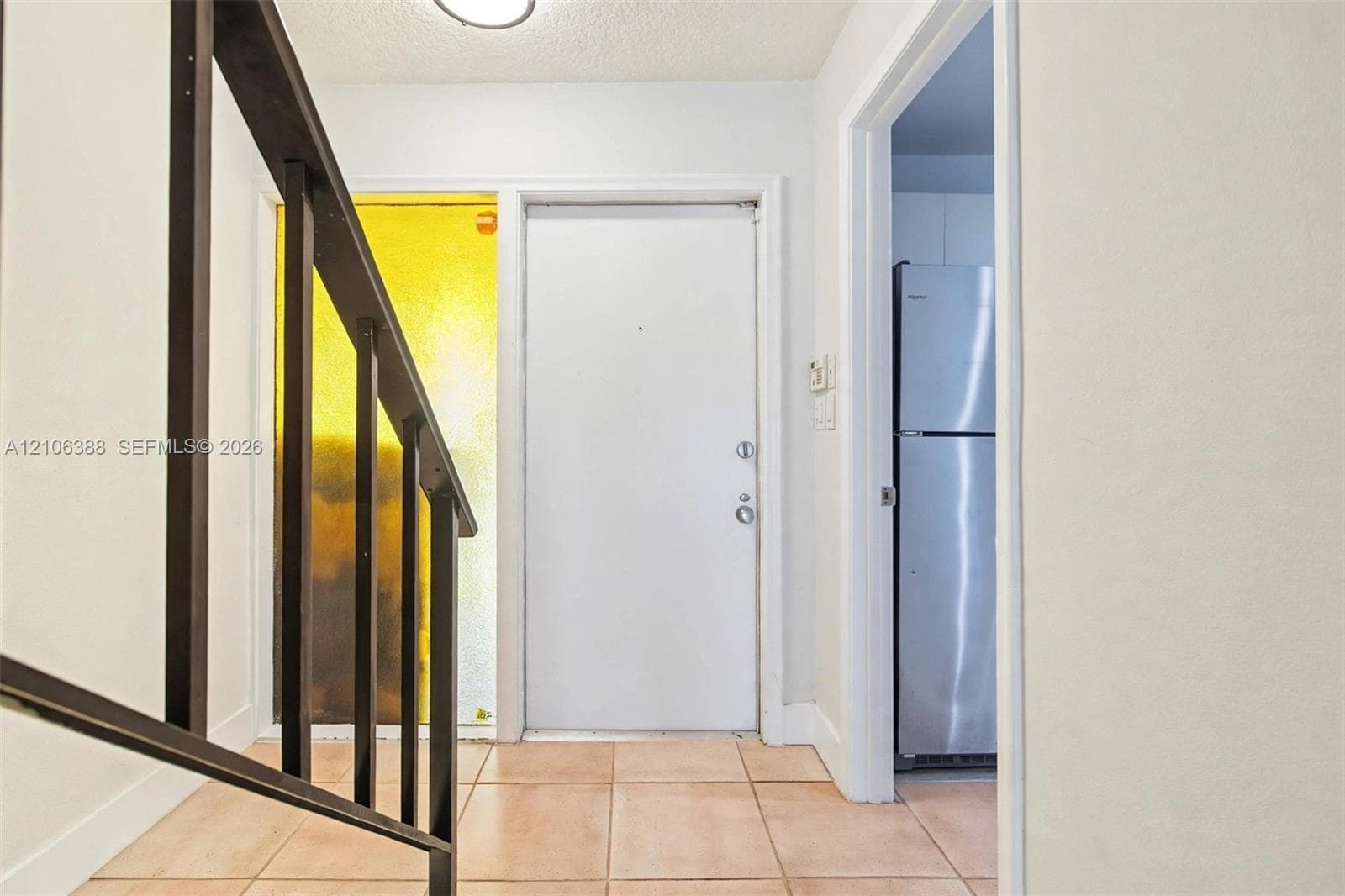 Entryway featuring tile flooring, a staircase with a dark-toned metal railing, a solid core entry door, and a textured glass sidelight
