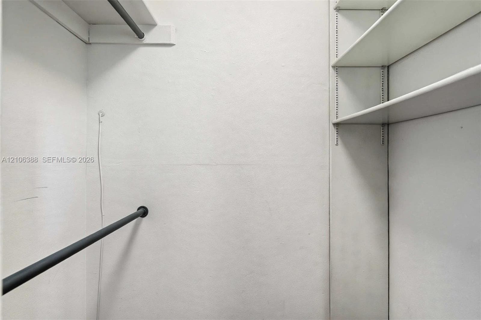 Storage area featuring adjustable shelving units, a horizontal hanging rod, and an overhead shelf