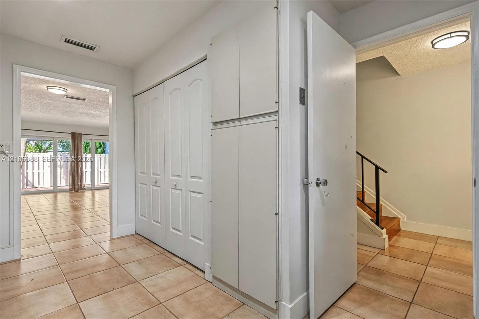 Ceramic tile flooring throughout, built-in floor-to-ceiling storage cabinetry, flush-mount lighting fixtures, and a staircase featuring a wooden handrail