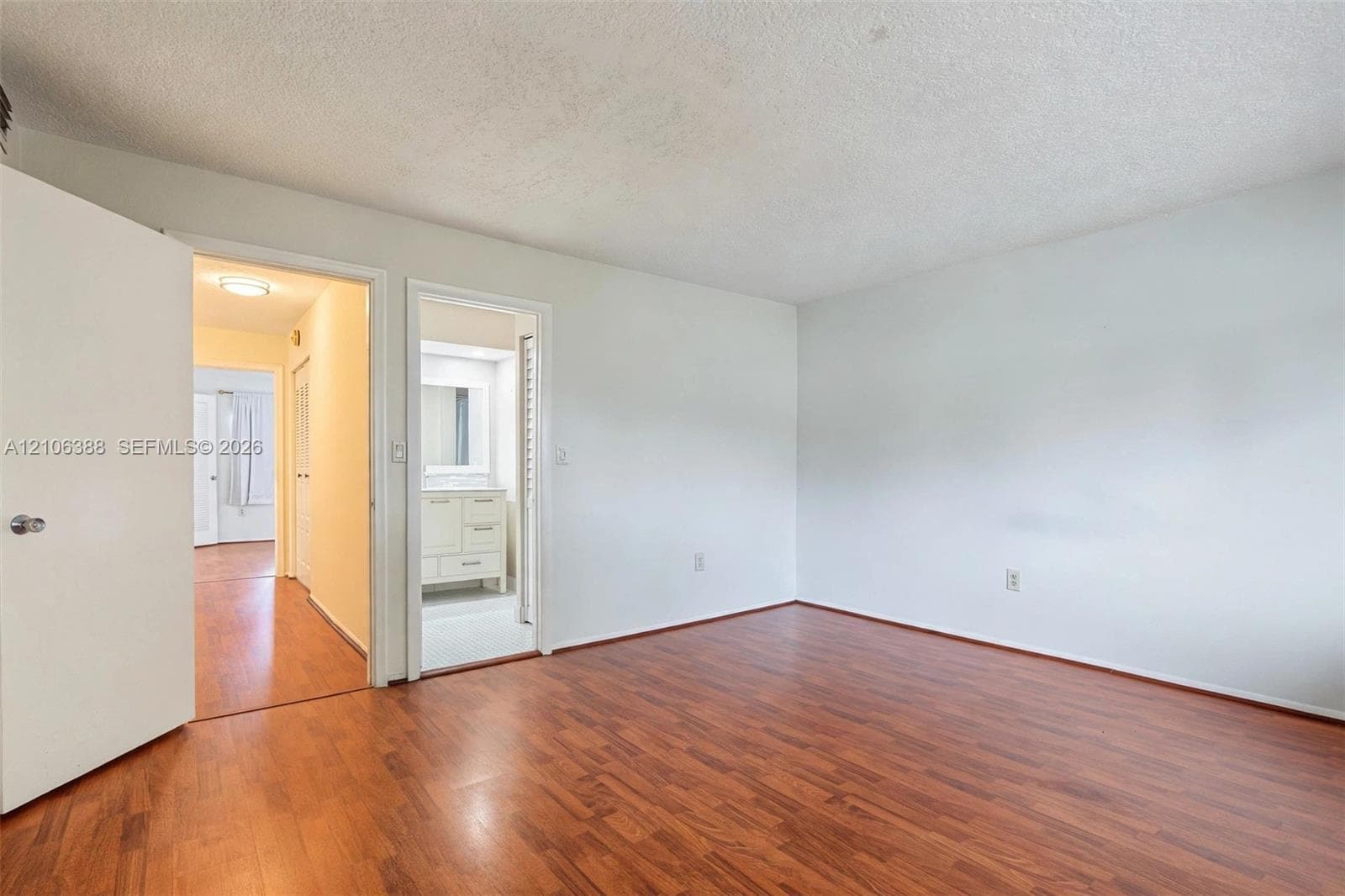 Room featuring wood-finish flooring, neutral walls, and solid-core interior doors