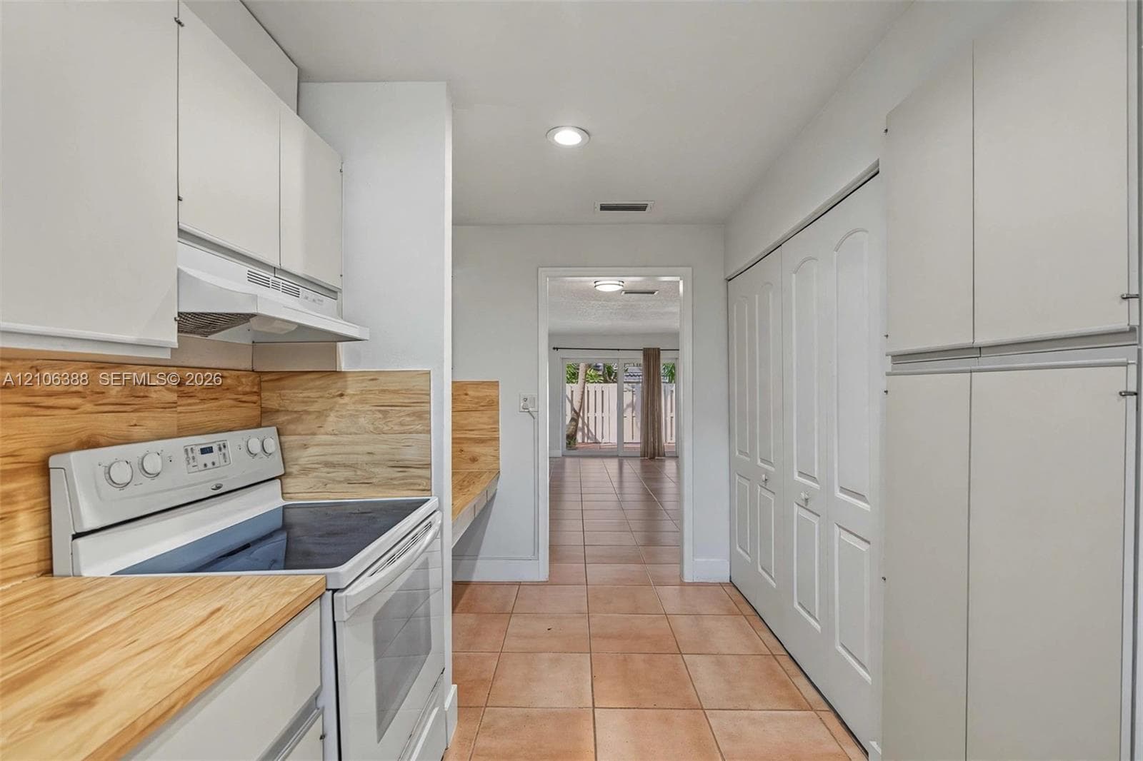 Kitchen featuring white cabinetry, wood-finish countertops, wood-finish backsplash, built-in electric range, and ceramic tile flooring
