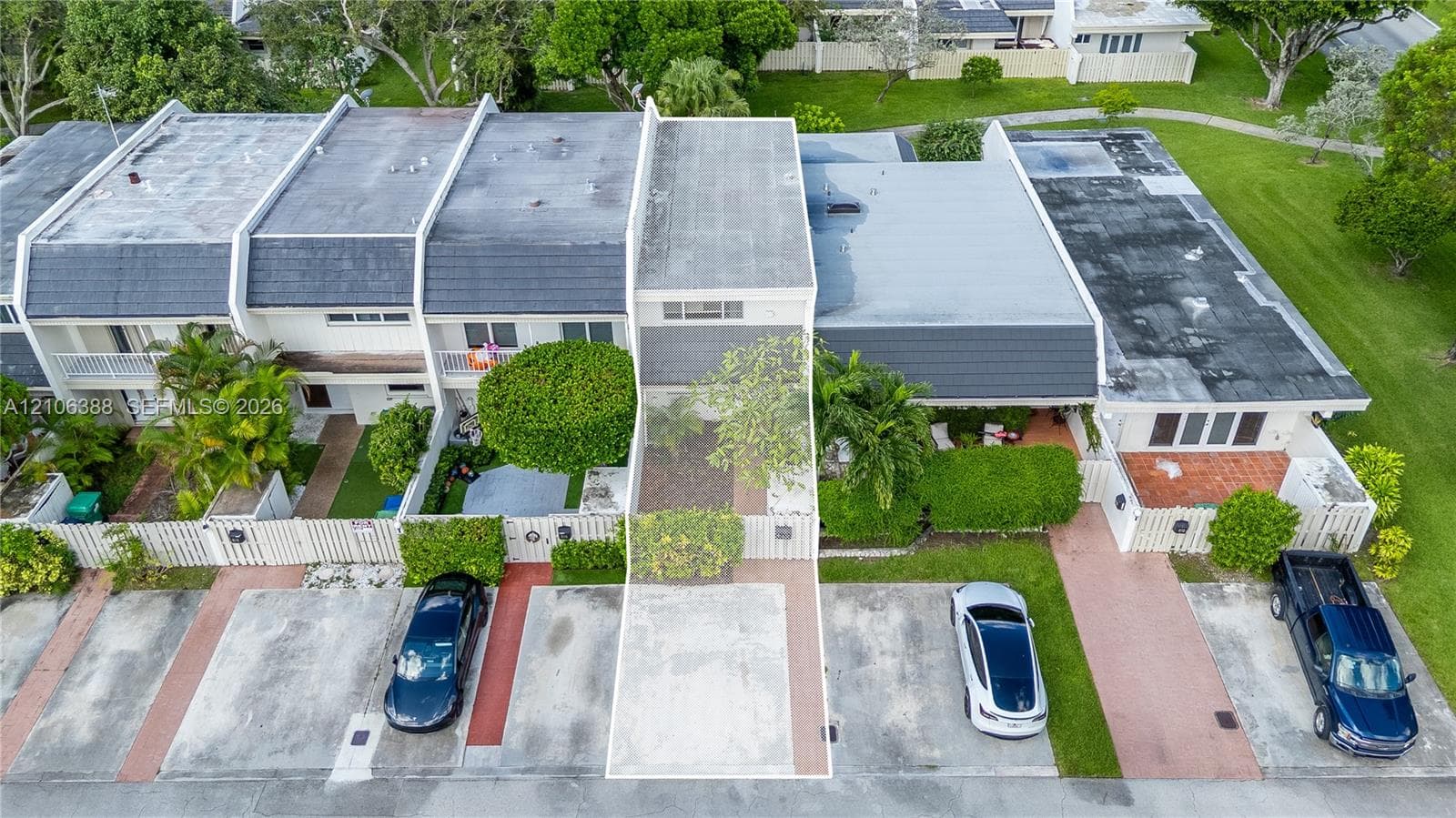 Two-story exterior featuring a private gated courtyard, dedicated concrete parking space, and mature perimeter landscaping