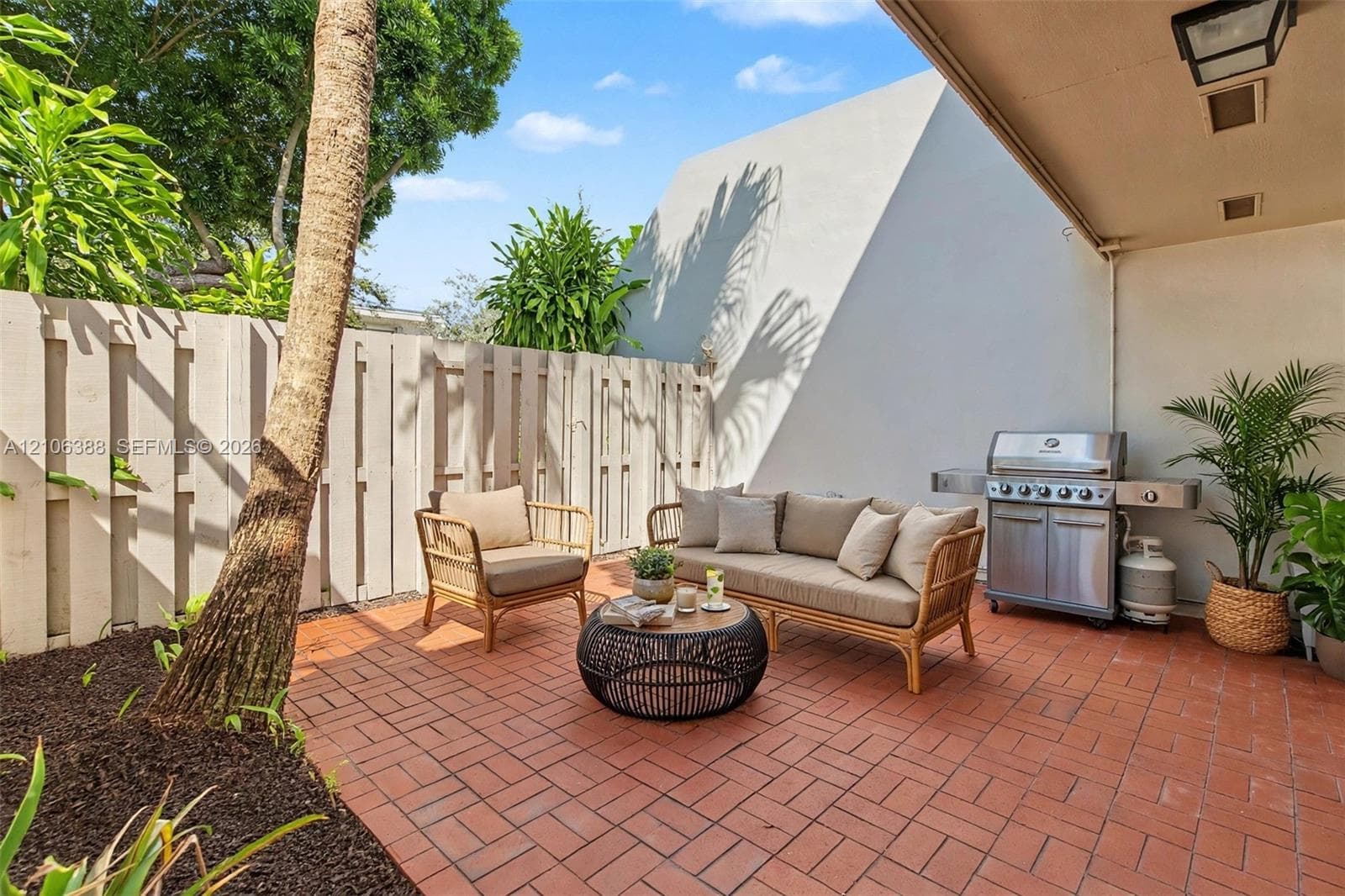 Covered patio featuring red brick paving, a built-in stainless steel outdoor grill, and a solid perimeter privacy fence