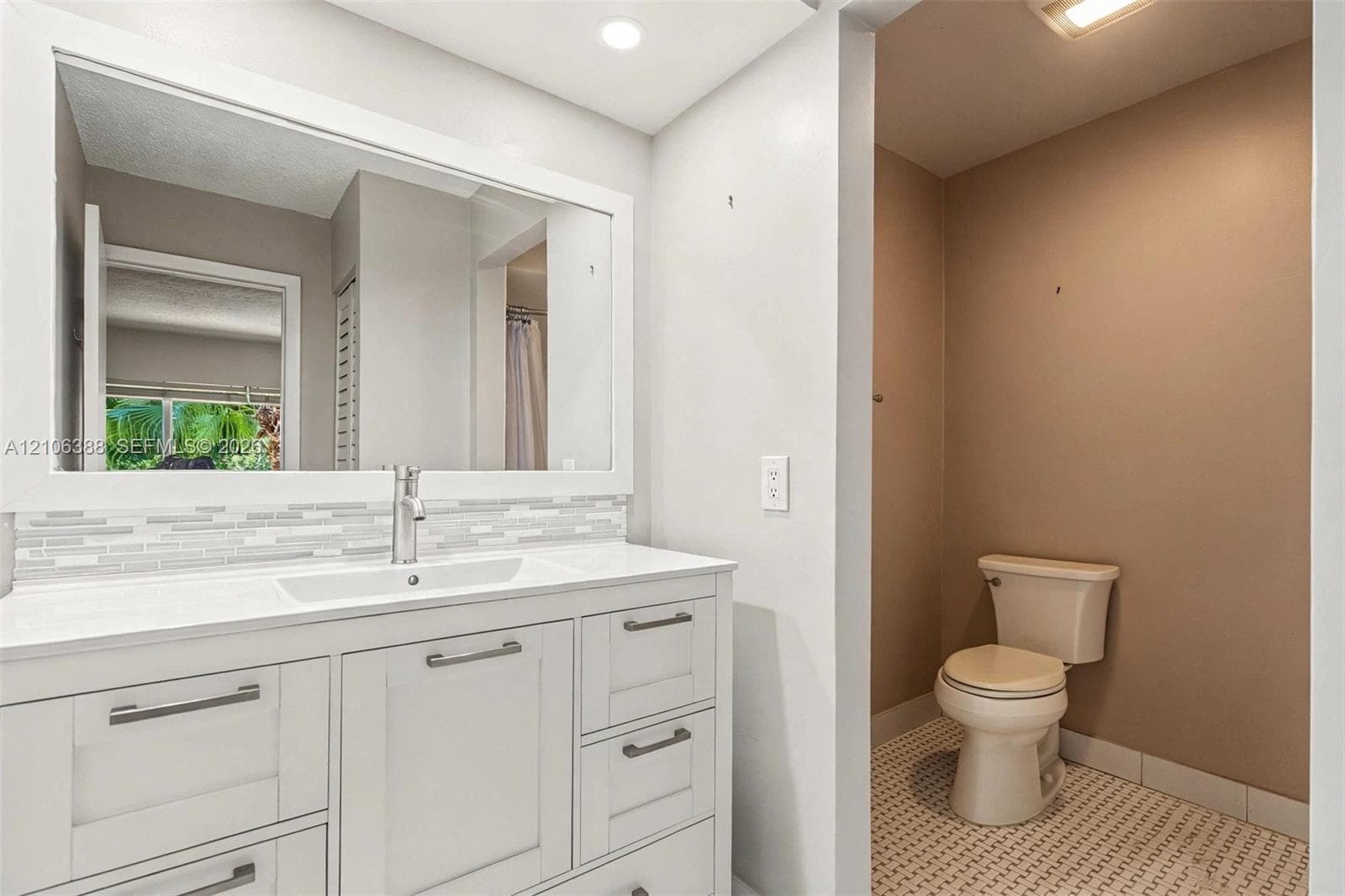 White shaker-style cabinetry with a smooth surface countertop, rectangular integrated basin, decorative glass tile backsplash, and oversized wall-mounted mirror