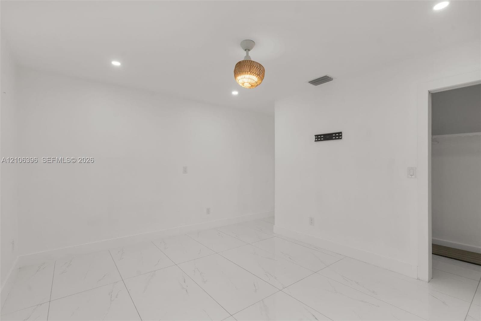 Large-format tile flooring, recessed ceiling lighting, and decorative semi-flush mount pendant fixture