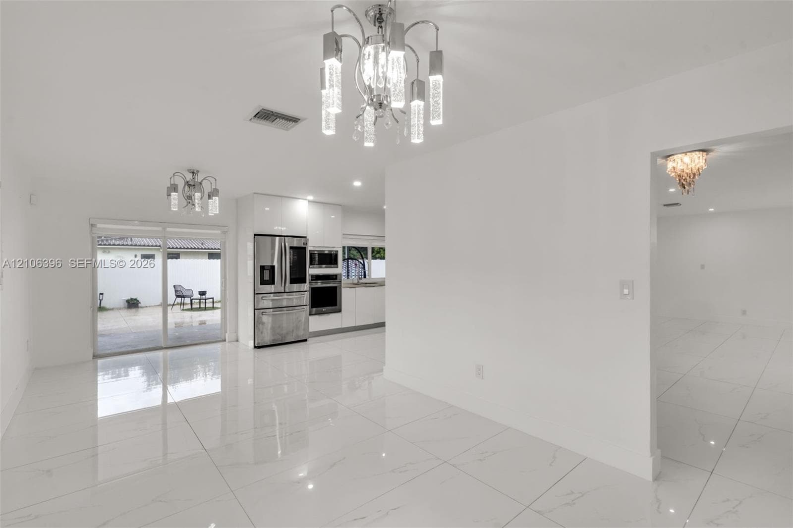 Large-format tile flooring, contemporary multi-tiered crystal chandeliers, stainless steel built-in kitchen appliances, and full-height glass sliding doors
