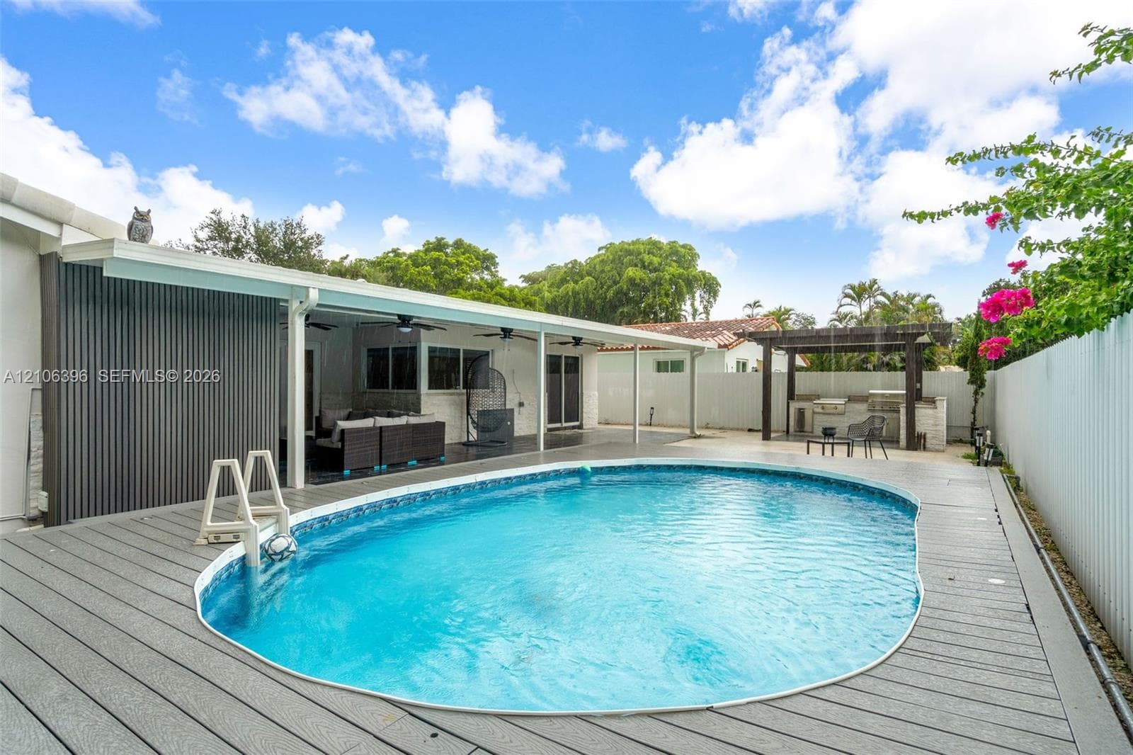 Backyard featuring an inground pool, composite decking, covered patio with recessed lighting, and a pergola-covered outdoor kitchen