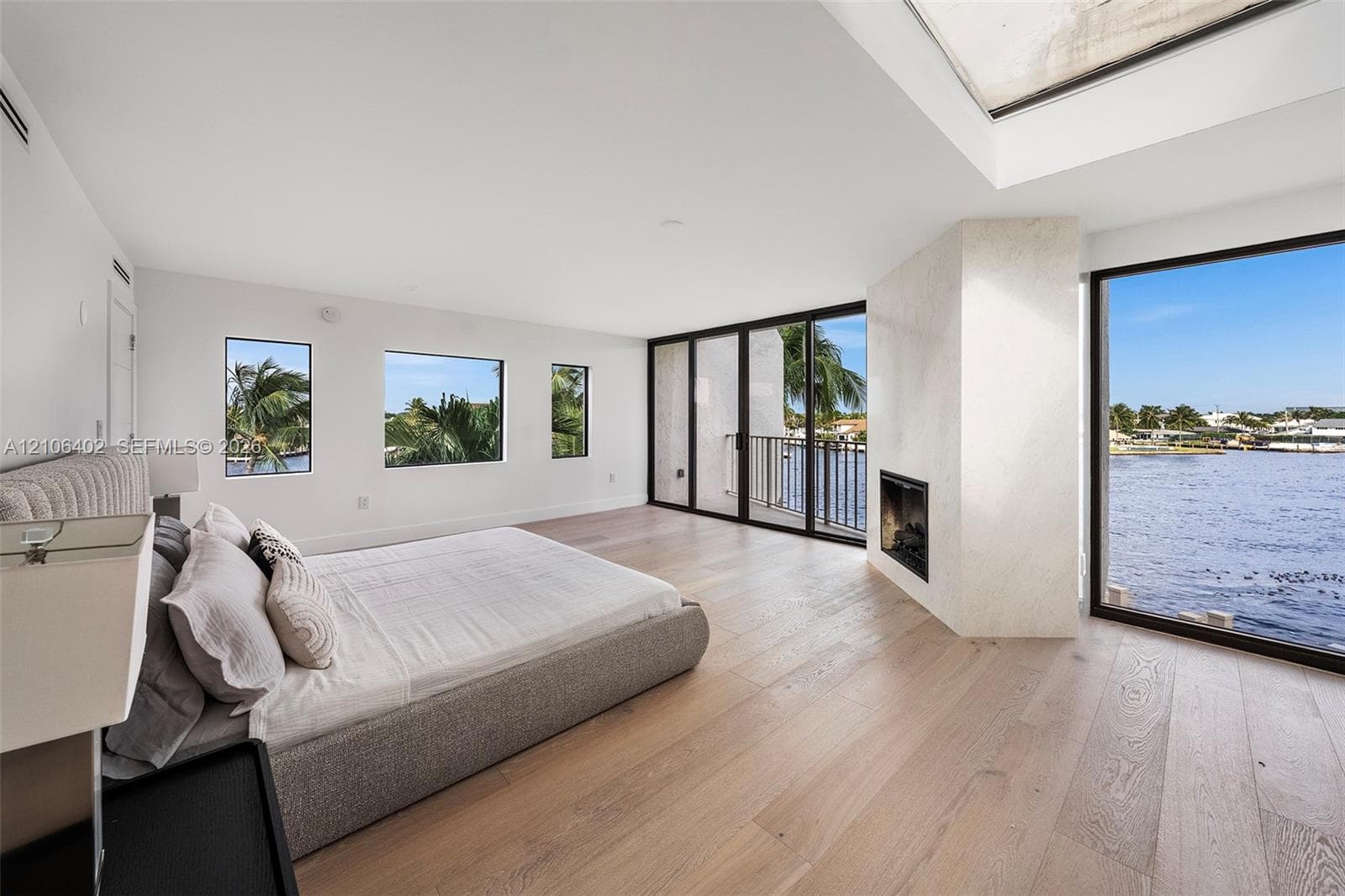 Wood-finish flooring, floor-to-ceiling glass paneling, interior fireplace with stone-textured surround, skylight, and multi-paned windows