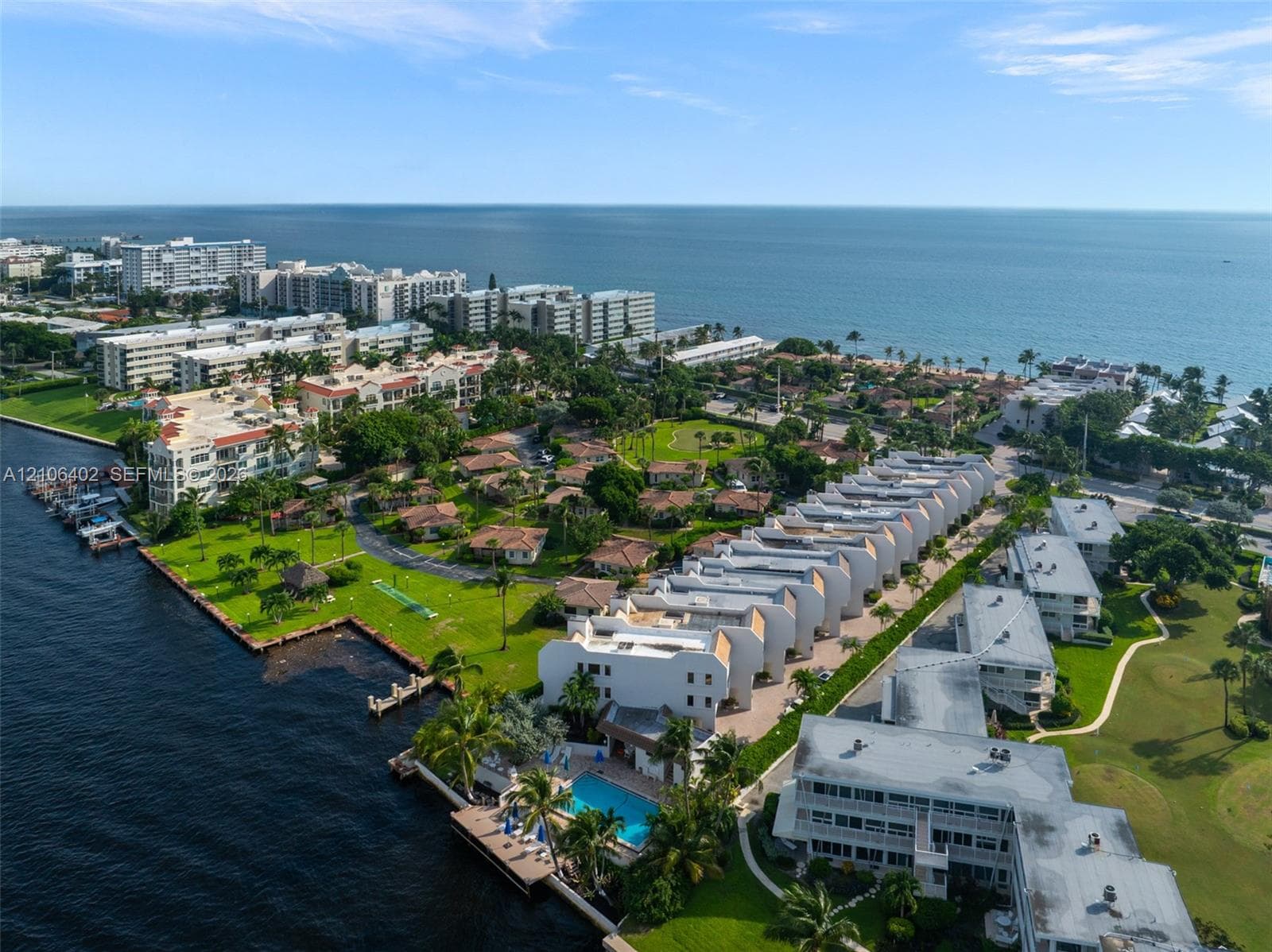 Waterfront residential complex featuring private boat slips, a swimming pool, mature palm trees, and expansive landscaped grounds
