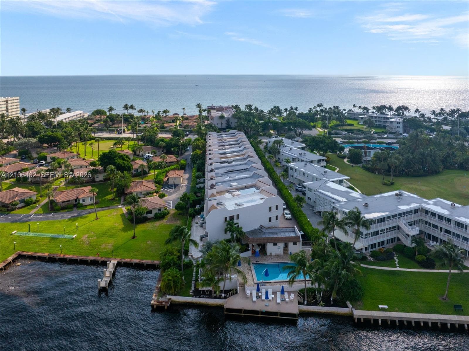 Waterfront multi-story residential complex featuring a swimming pool, private wooden dock, and extensive landscaped grounds