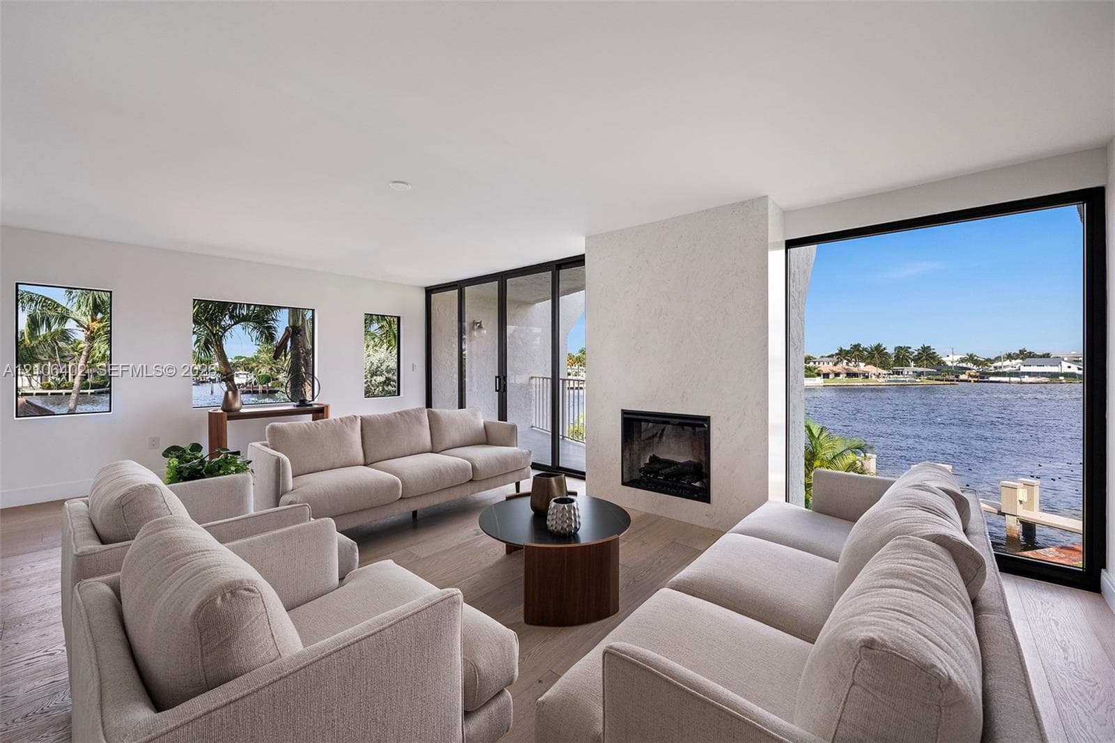 Living area featuring wood-finish flooring, floor-to-ceiling glass wall panels, and a centrally positioned fireplace with a light-toned surround