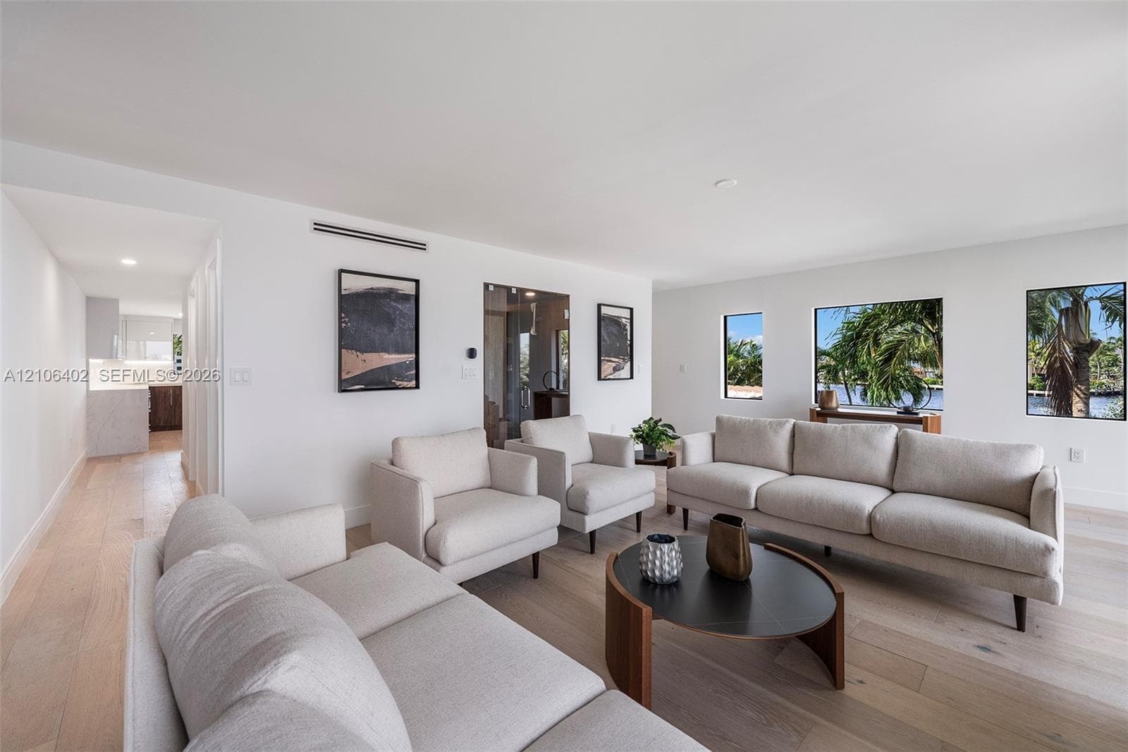 Living area featuring light wood-finish flooring, recessed ceiling lighting, and large windows with outdoor scenery