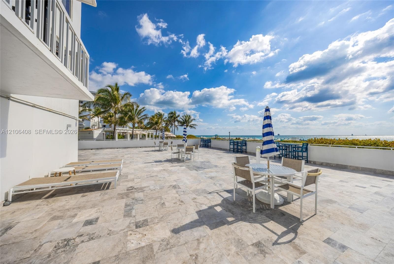 Expansive stone-paved terrace featuring a white metal perimeter railing and coastal horizon