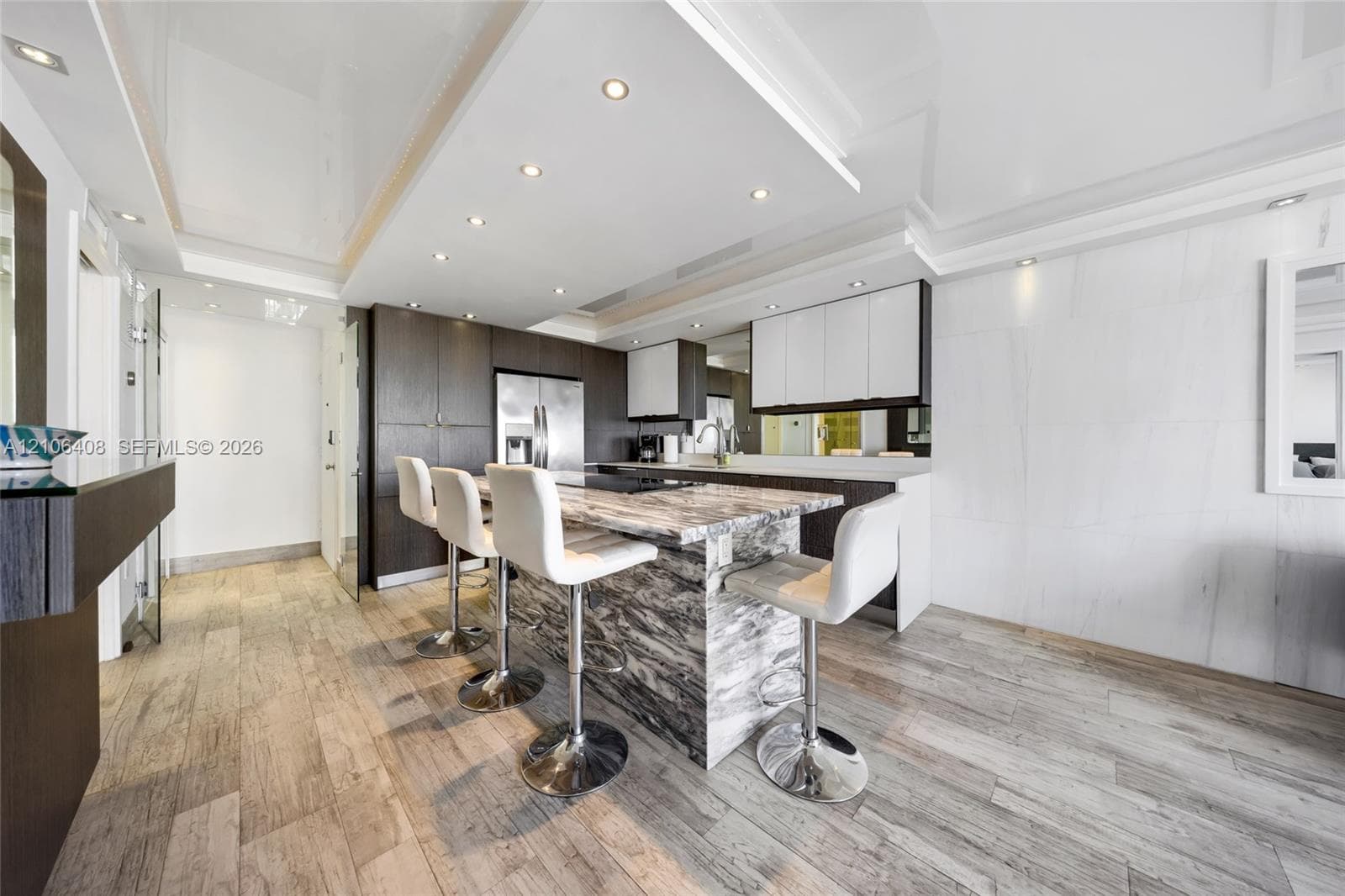 Kitchen featuring stone-finish waterfall island, wood-finish flooring, recessed ceiling lighting, two-tone cabinetry, and built-in stainless steel appliances