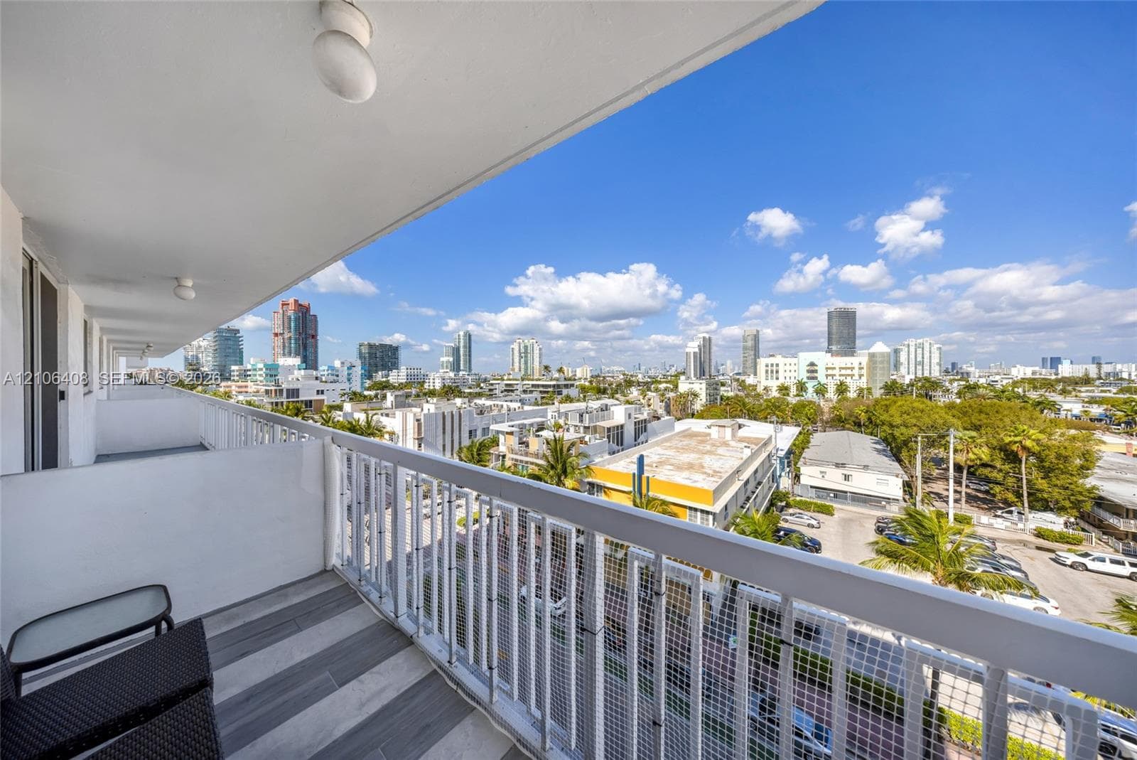 Covered balcony featuring grey-toned tile flooring, a white metal railing, and a sprawling urban skyline backdrop