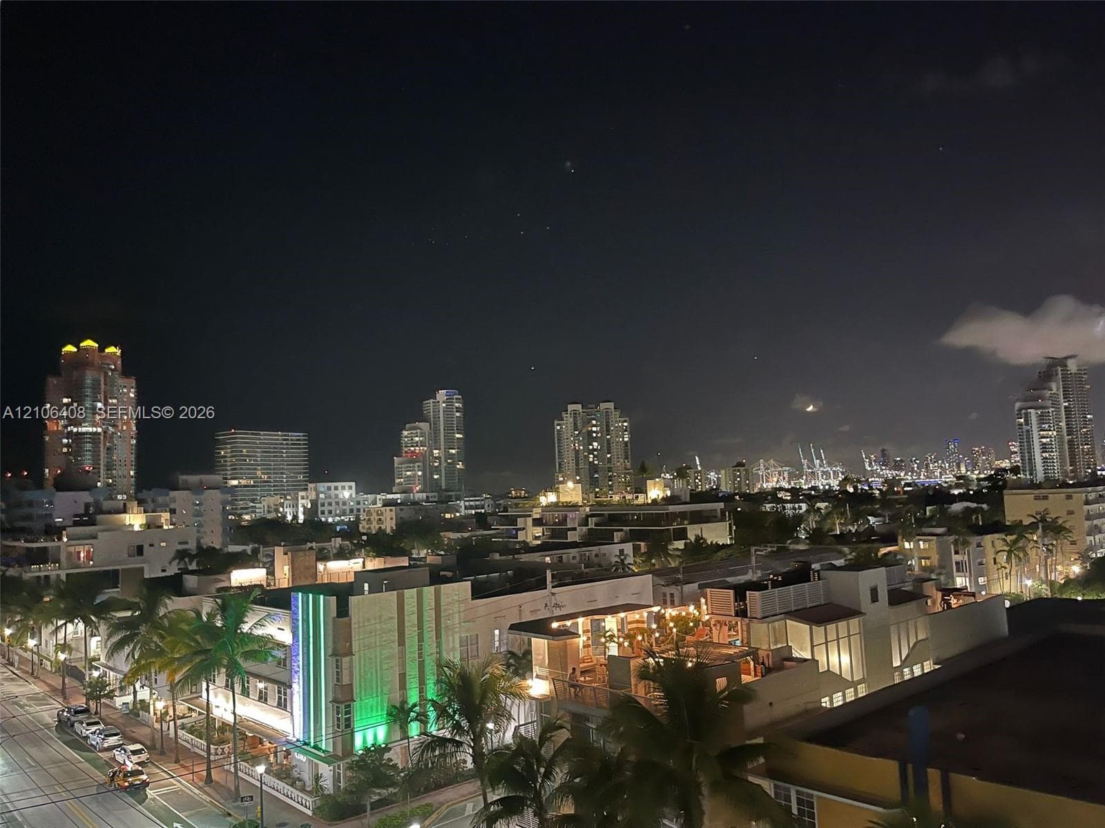 Urban skyline backdrop featuring illuminated high-rise buildings and mature palm trees