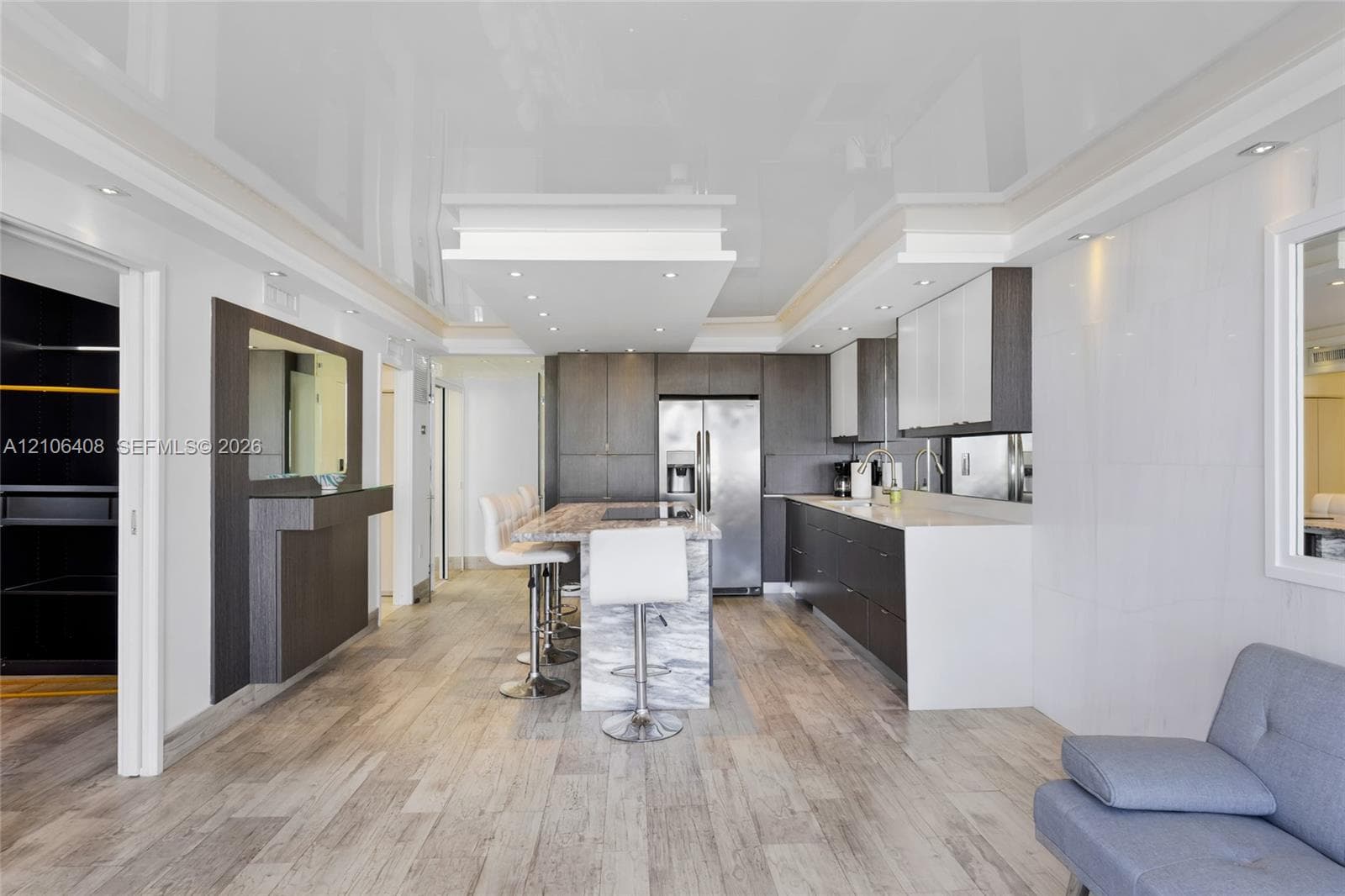 Kitchen featuring a stone-topped island with seating, dark wood-finish cabinetry, a high-gloss ceiling with recessed lighting, and wood-finish flooring