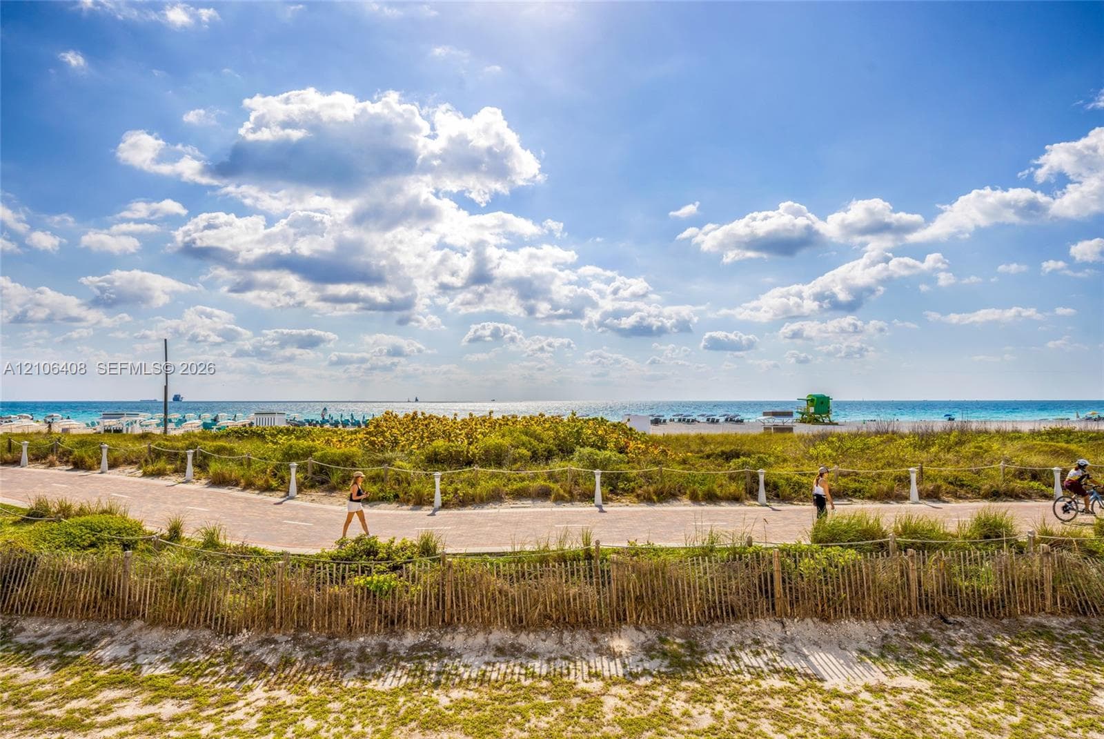Oceanfront property featuring direct access to a paved coastal path, native dune vegetation, and wooden perimeter fencing