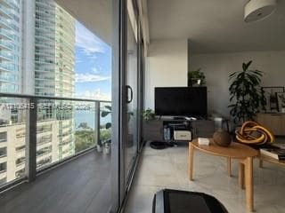 Full-height sliding glass doors opening to a private balcony with glass railings, polished stone flooring, and built-in ceiling lighting
