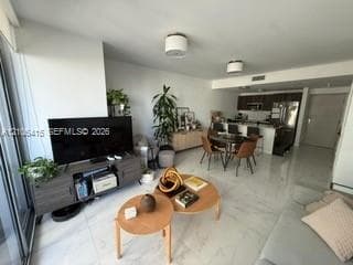 Open-concept floor plan featuring large-format polished tile flooring, recessed and drum-style ceiling lighting, and a kitchen island with stone-finish countertops