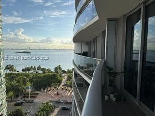 Curved balcony featuring glass railings, floor-to-ceiling windows, and expansive waterfront scenery
