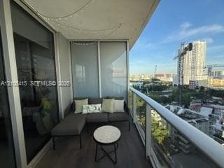 Private balcony featuring wood-finish flooring, a glass panel railing, and full-height sliding glass doors